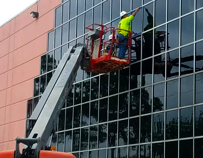 A man is cleaning the windows of a building with a crane.