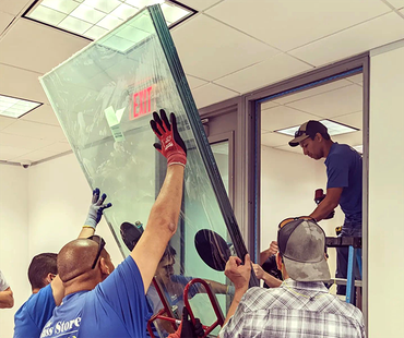 A group of men are installing a glass door in a building.