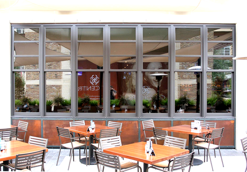 A restaurant with tables and chairs in front of a large window.