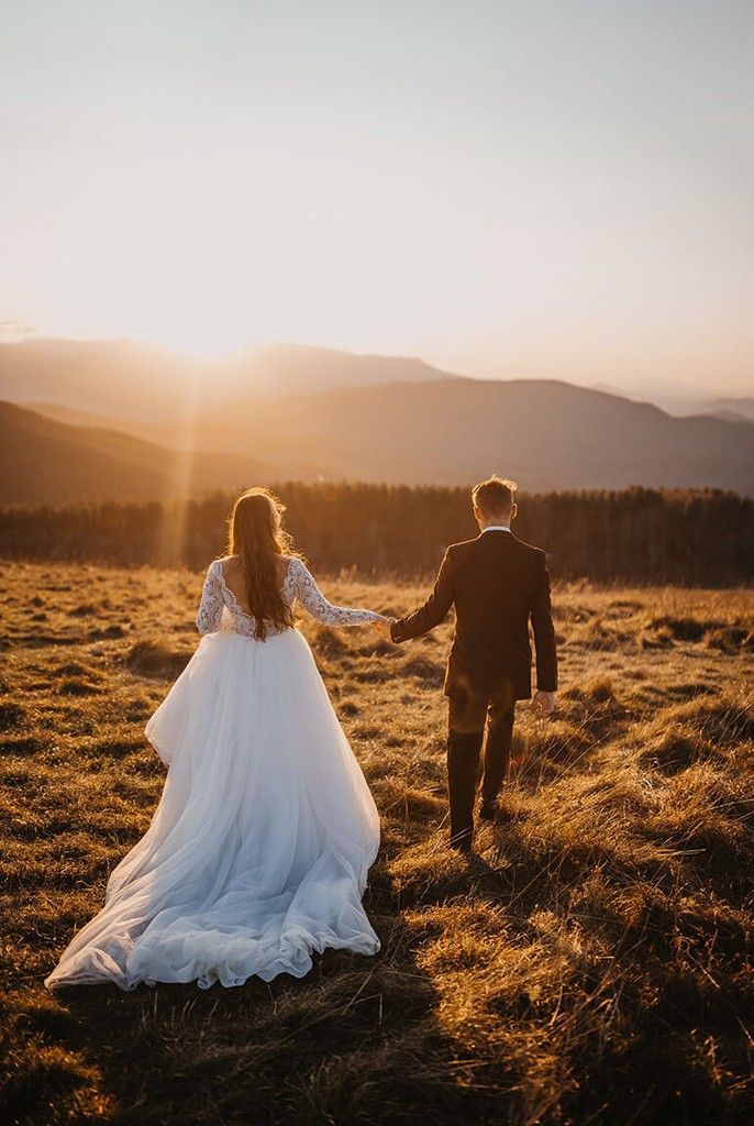 Bride and groom walking hand in hand through a golden field at sunset