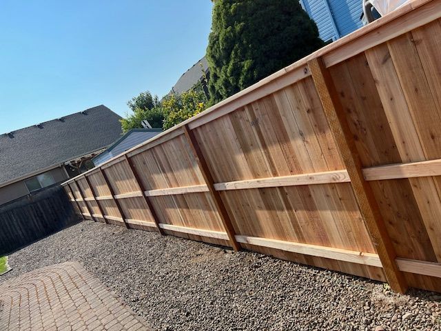 Backyard hardwood fencing with gravel walkway and paver edge in Salem, OR landscaping project
