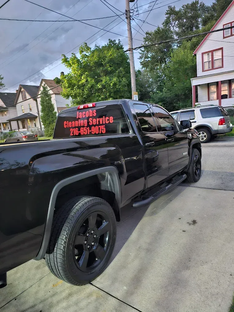 Man wearing pink gloves, holding cleaning supplies, surprised expression.