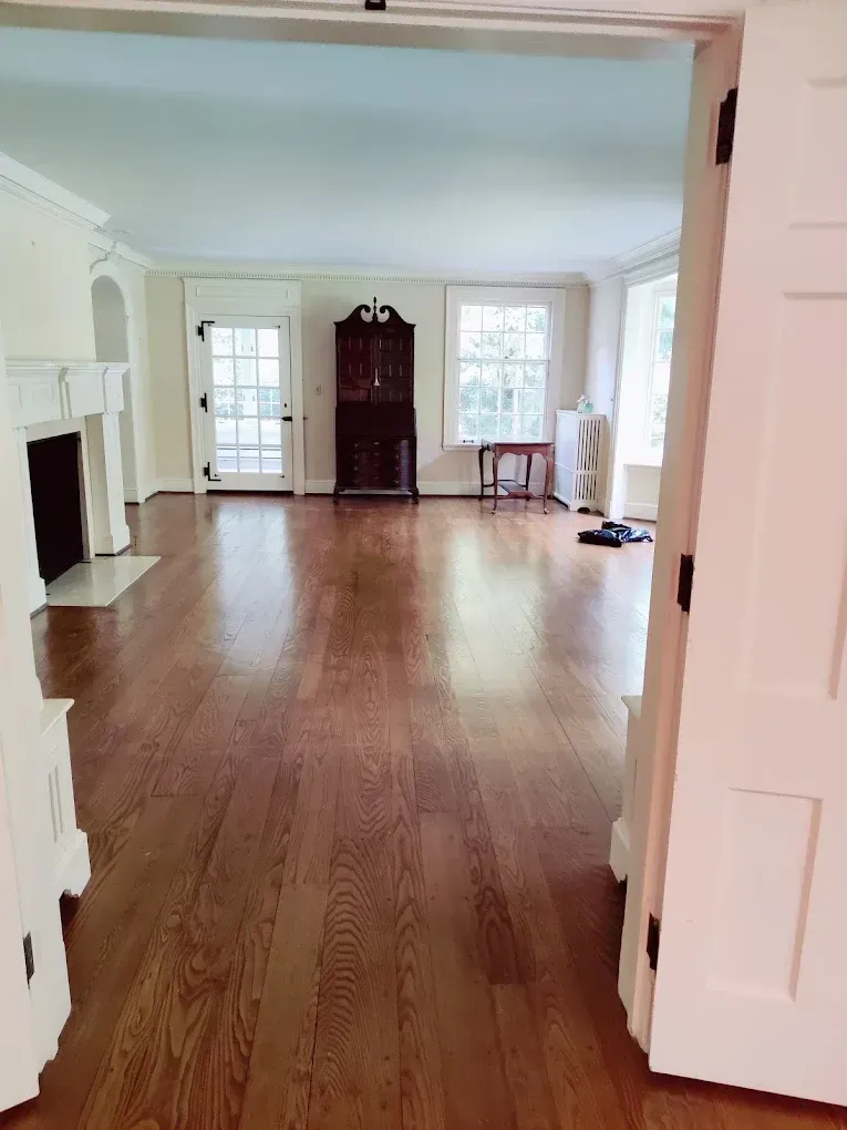 Empty room with hardwood floors, white trim, and a dark cabinet.