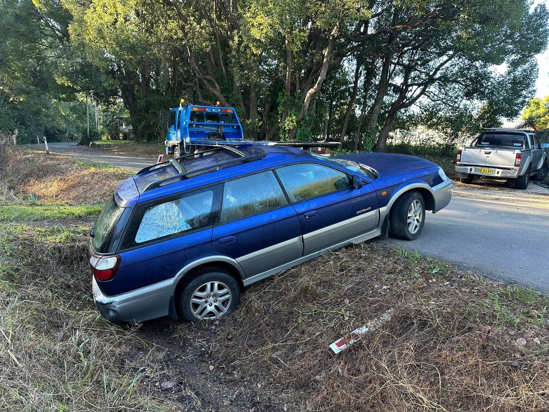 Blue station wagon parked on a grassy slope near trees, with a bike rack on top — Bangalow Towing in Bangalow, NSW