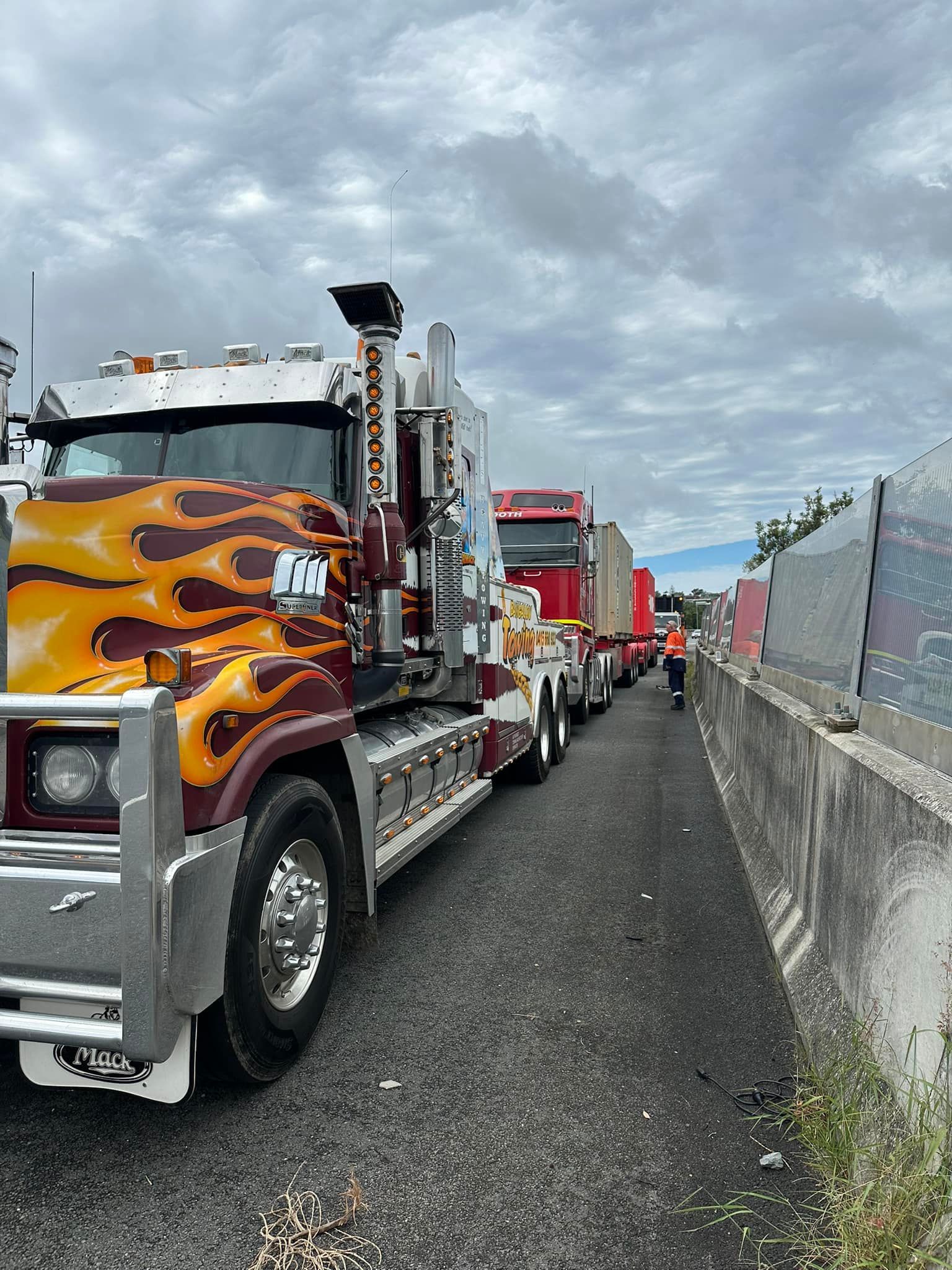 Trucks lined up on the side of a road, one with flame design — Bangalow Towing in Bangalow, NSW