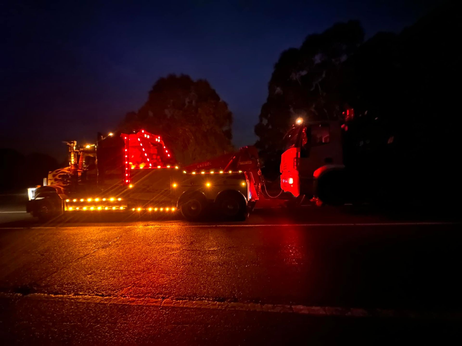 Tow Truck With Bright Orange Lights Parked on a Wet Road — Bangalow Towing in Bangalow, NSW
