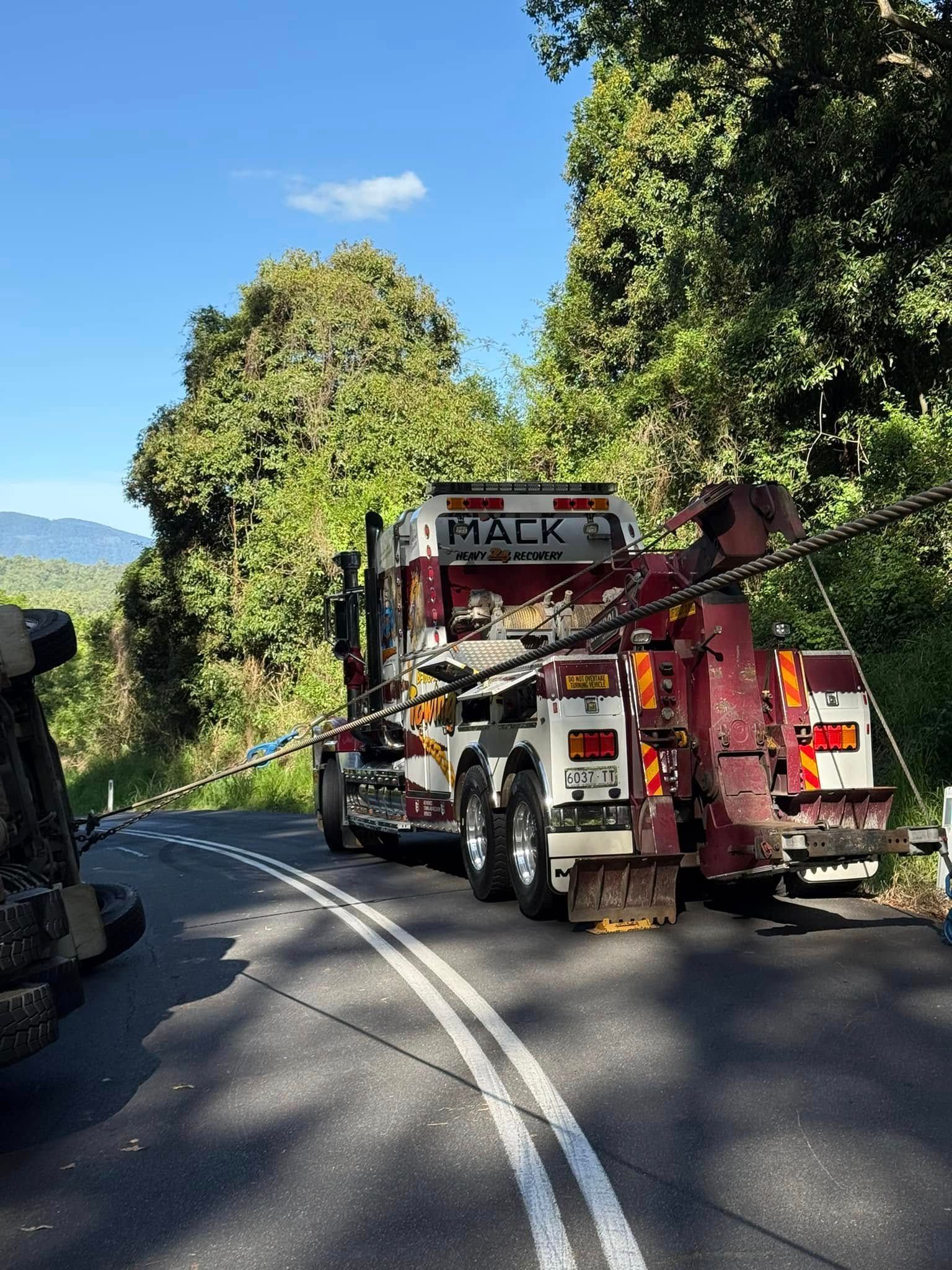 Mack Tow Truck on a Winding Road, Assisting a Tipped-over Truck — Bangalow Towing in Bangalow, NSW