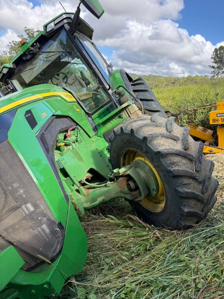 Green John Deere Tractor Tilted on Its Side in a Field — Bangalow Towing in Bangalow, NSW