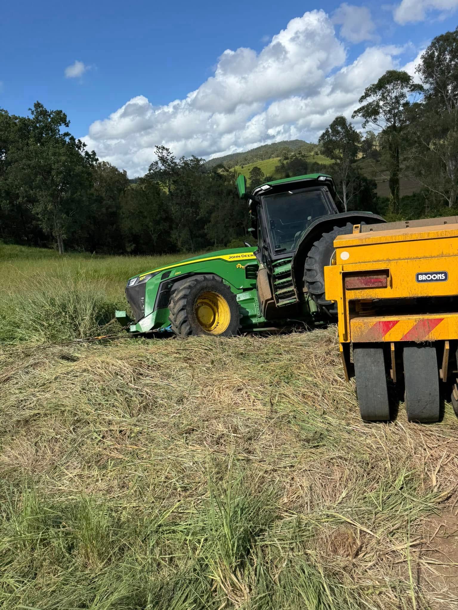 Green Tractor in a Field Pulling a Yellow Trailer — Bangalow Towing in Bangalow, NSW