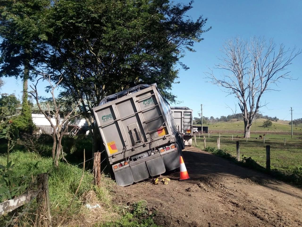 Truck trailer tipped on its side on a dirt road, next to a fence — Bangalow Towing in Bangalow, NSW