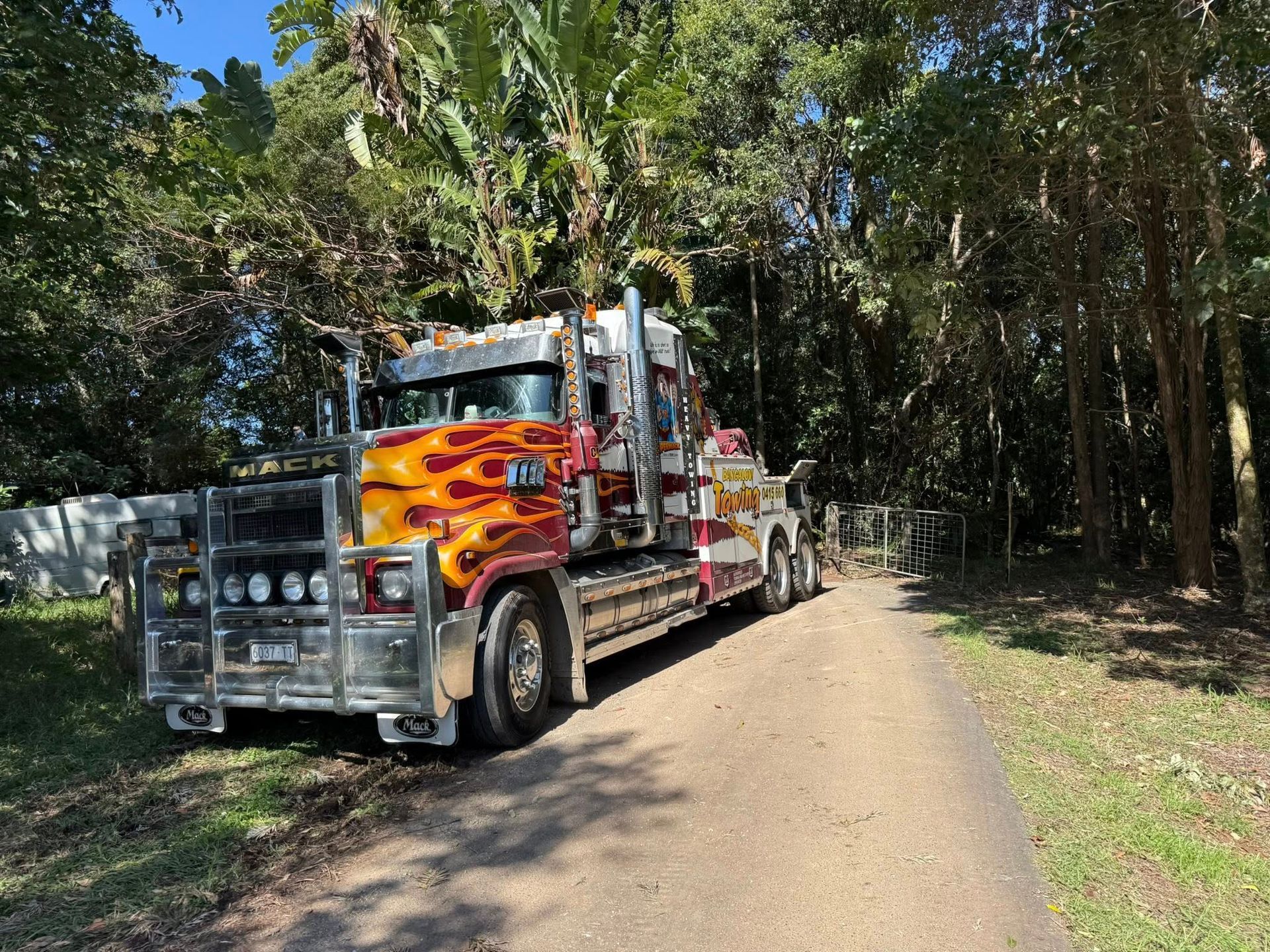 Large, flame-painted semi-truck parked on a dirt path, surrounded by trees — Bangalow Towing in Bangalow, NSW