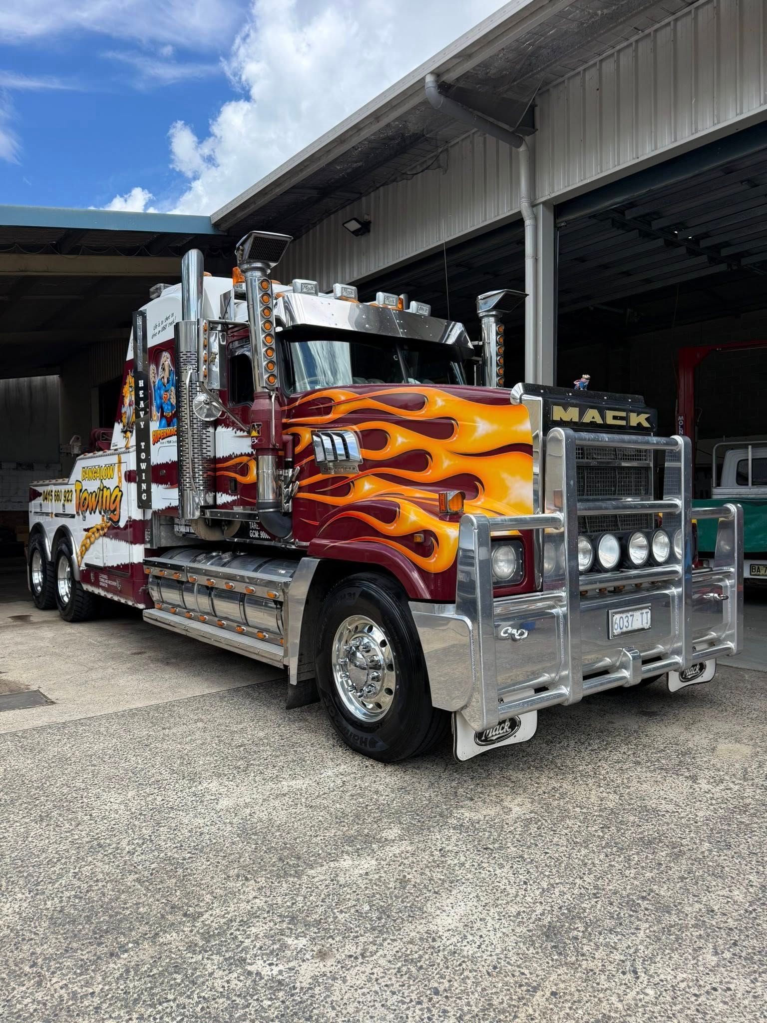 Custom chrome tow truck with orange flame graphics parked in a garage bay — Bangalow Towing in Bangalow, NSW