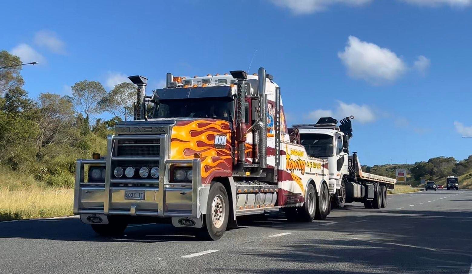 Tow truck with orange flames design driving on a road under a blue sky — Bangalow Towing in Bangalow, NSW