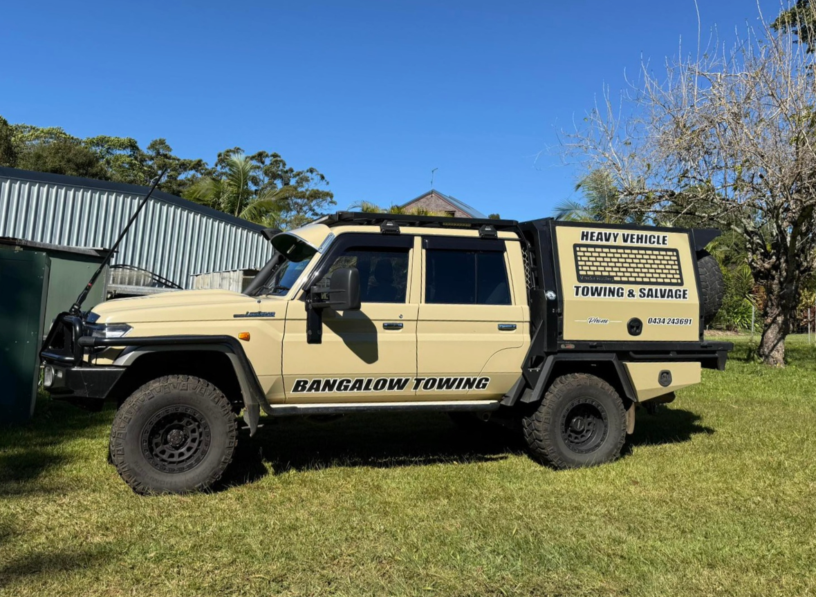 Tan 4x4 pickup truck parked on grass beside a building under a blue sky — Bangalow Towing in Bangalow, NSW