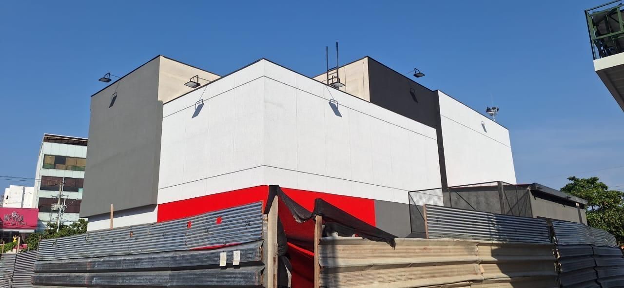 Un edificio con una franja roja y blanca en el costado está en construcción.