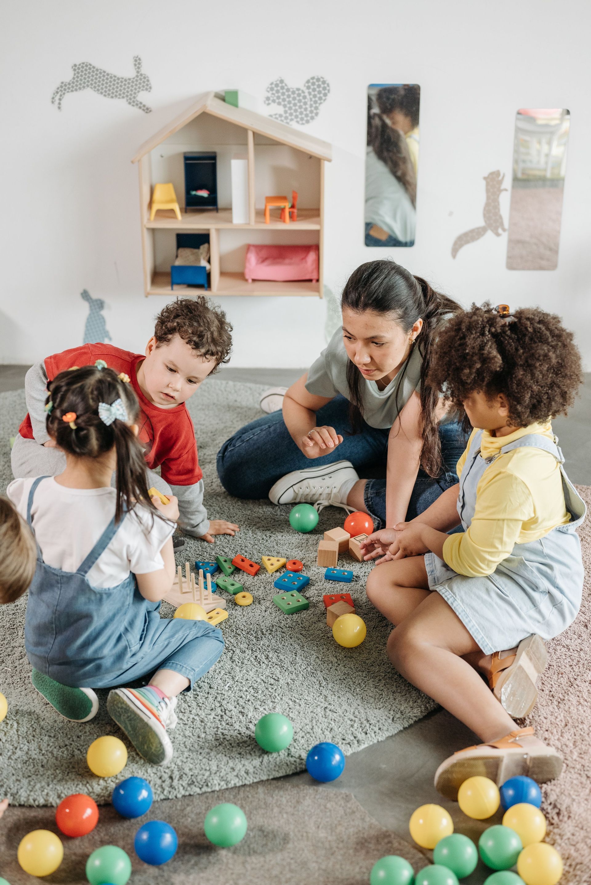 Children playing with colorful blocks on a carpet beside an adult in a cozy playroom