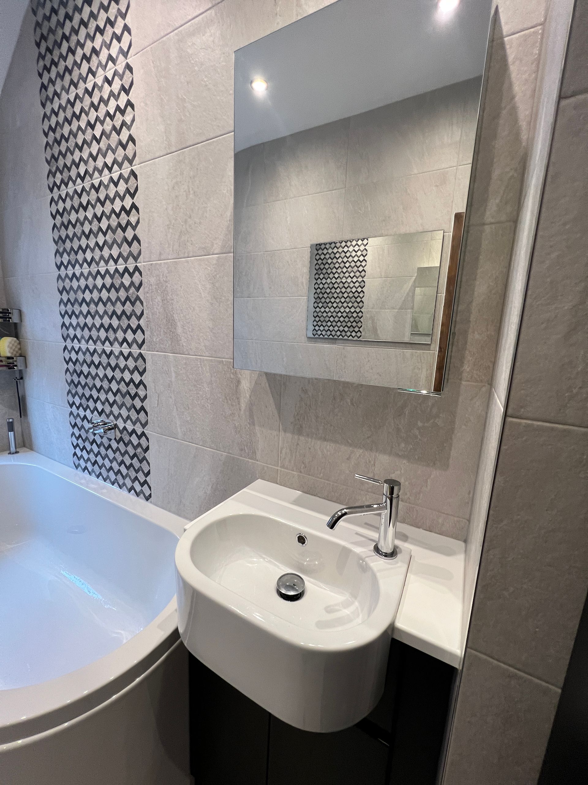 A bathroom with a sink , tub and mirror.
