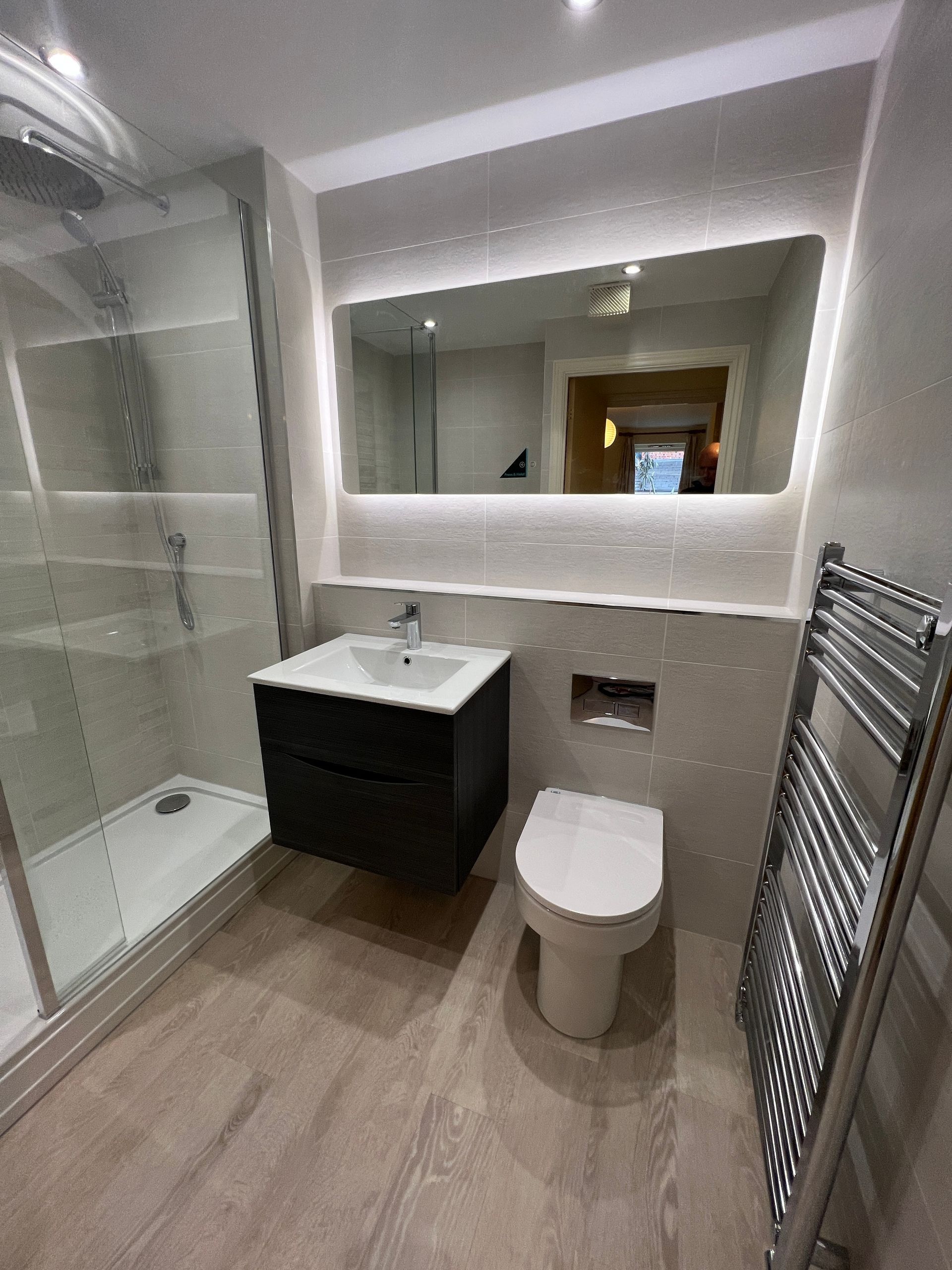 A bathroom with a toilet , sink , shower and mirror.