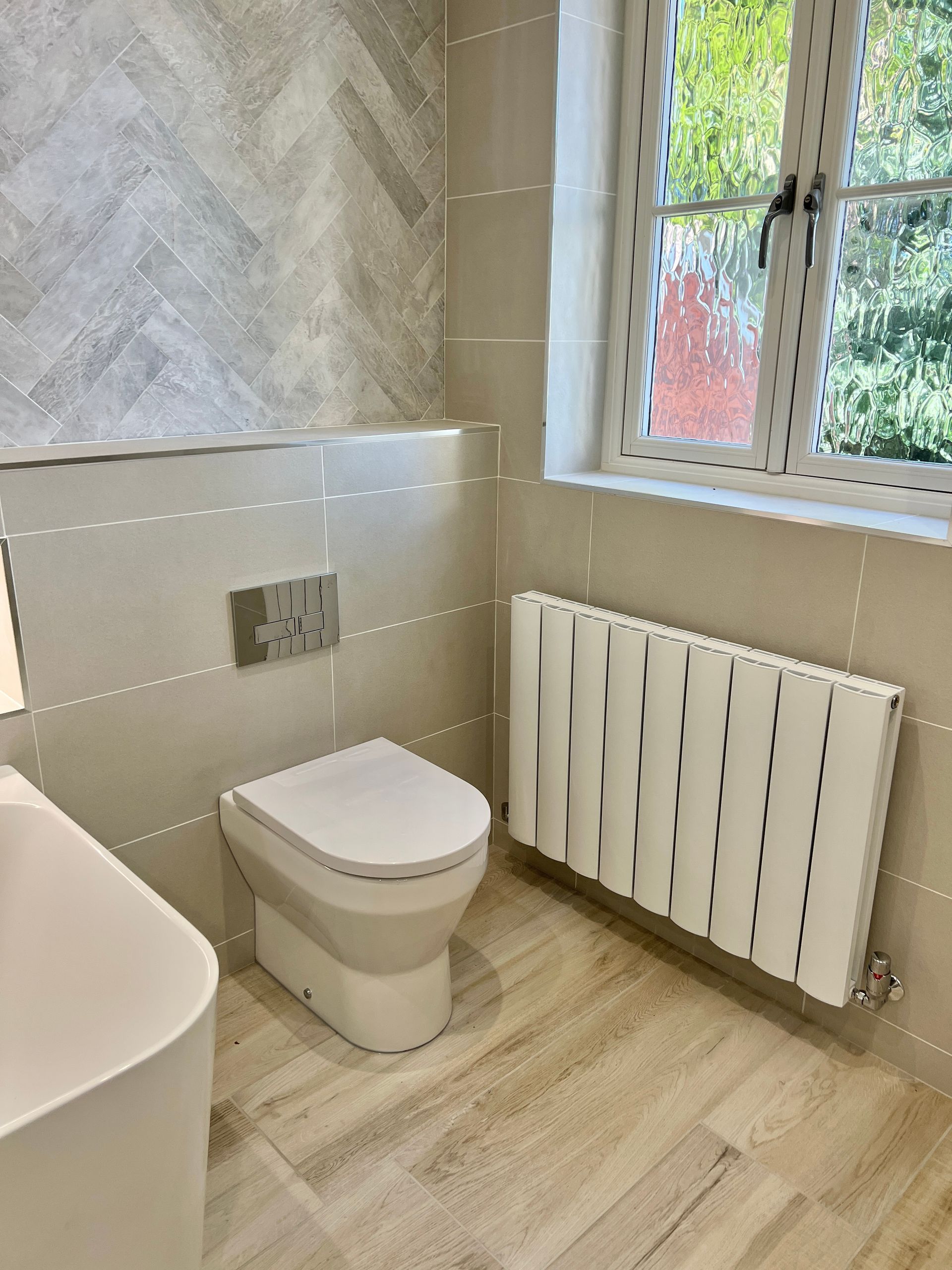 A bathroom with a toilet , sink , and radiator.
