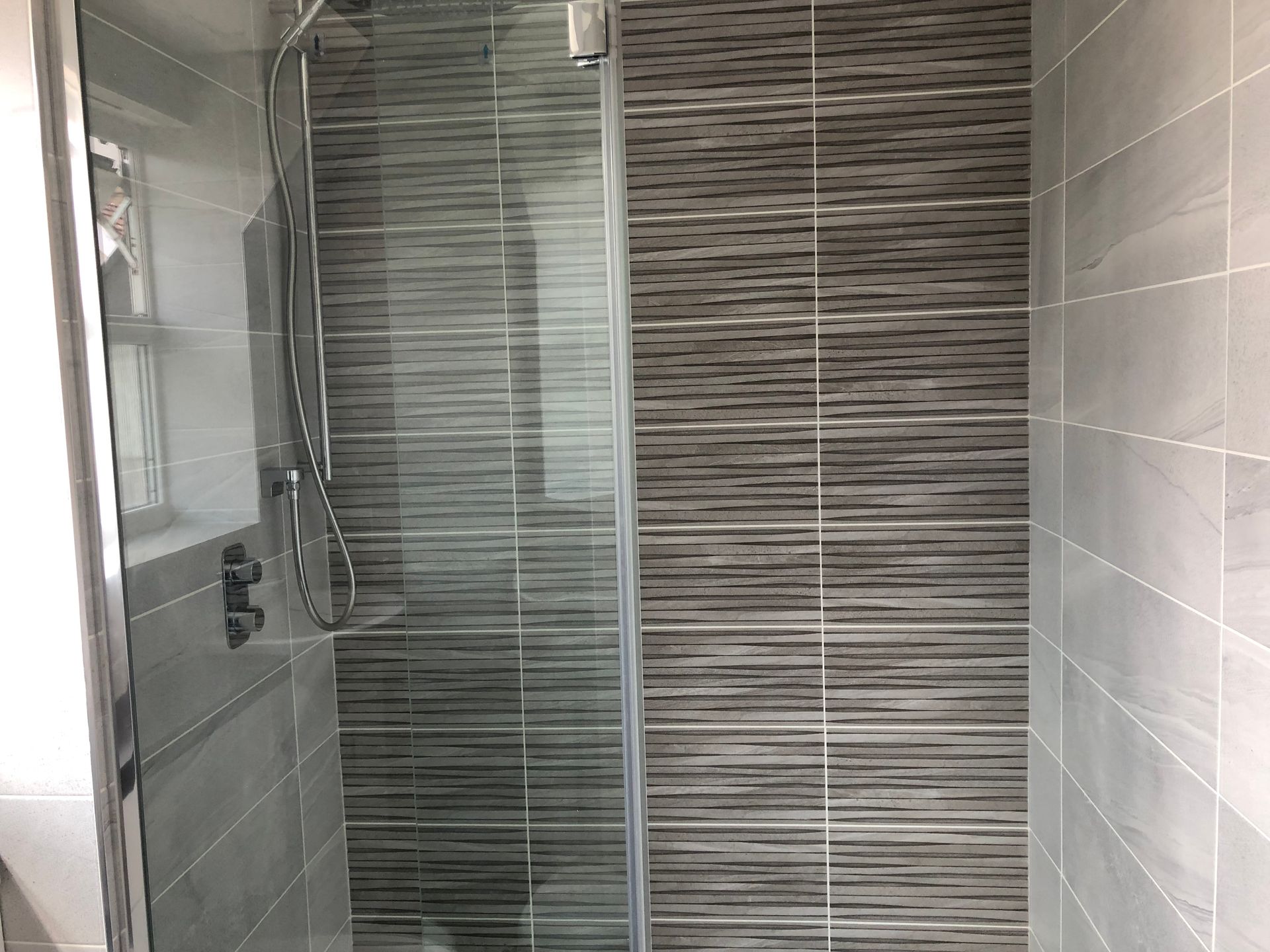 A bathroom with a walk in shower with a glass door.