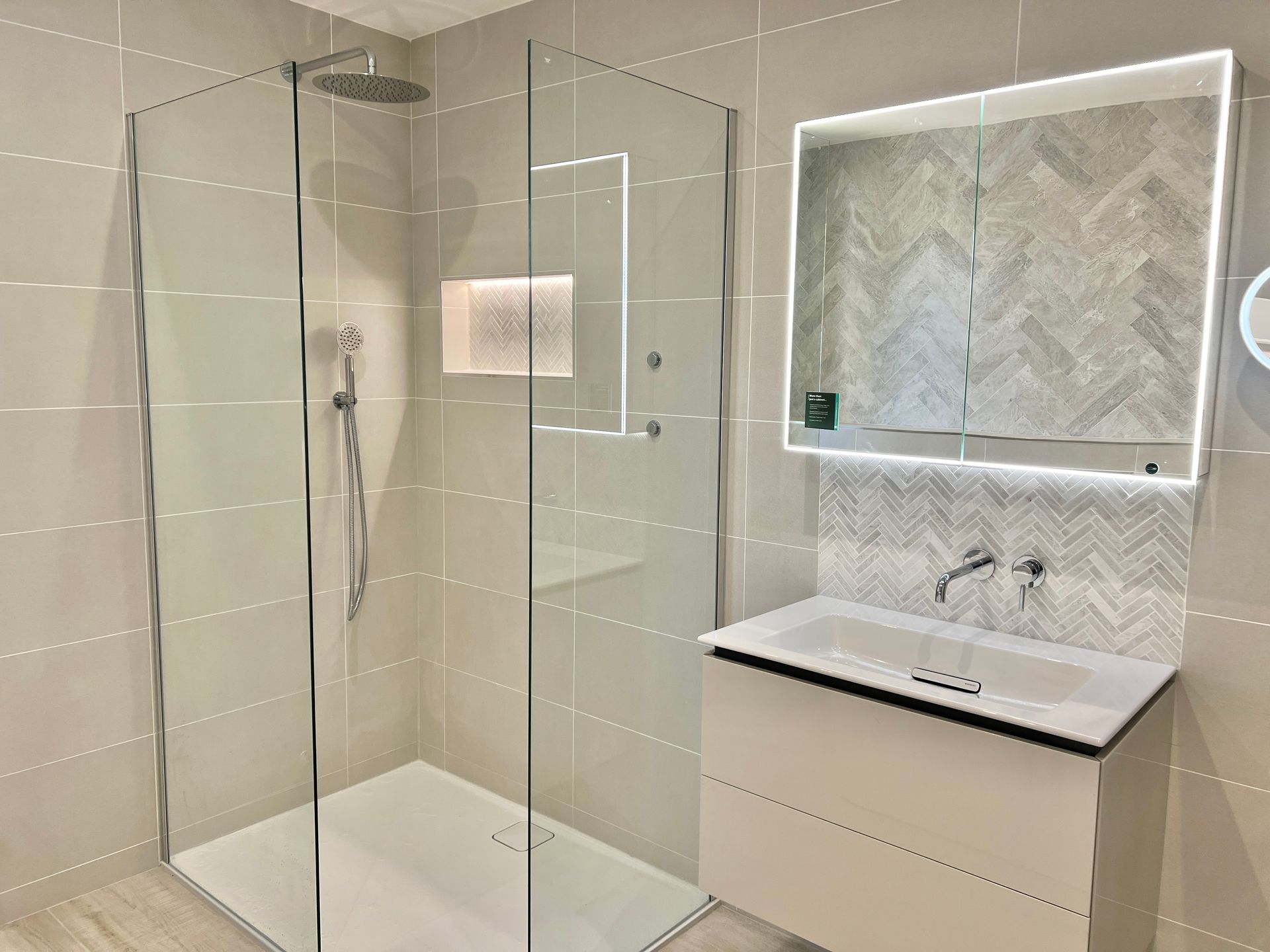 A bathroom with a walk in shower , sink and mirror.