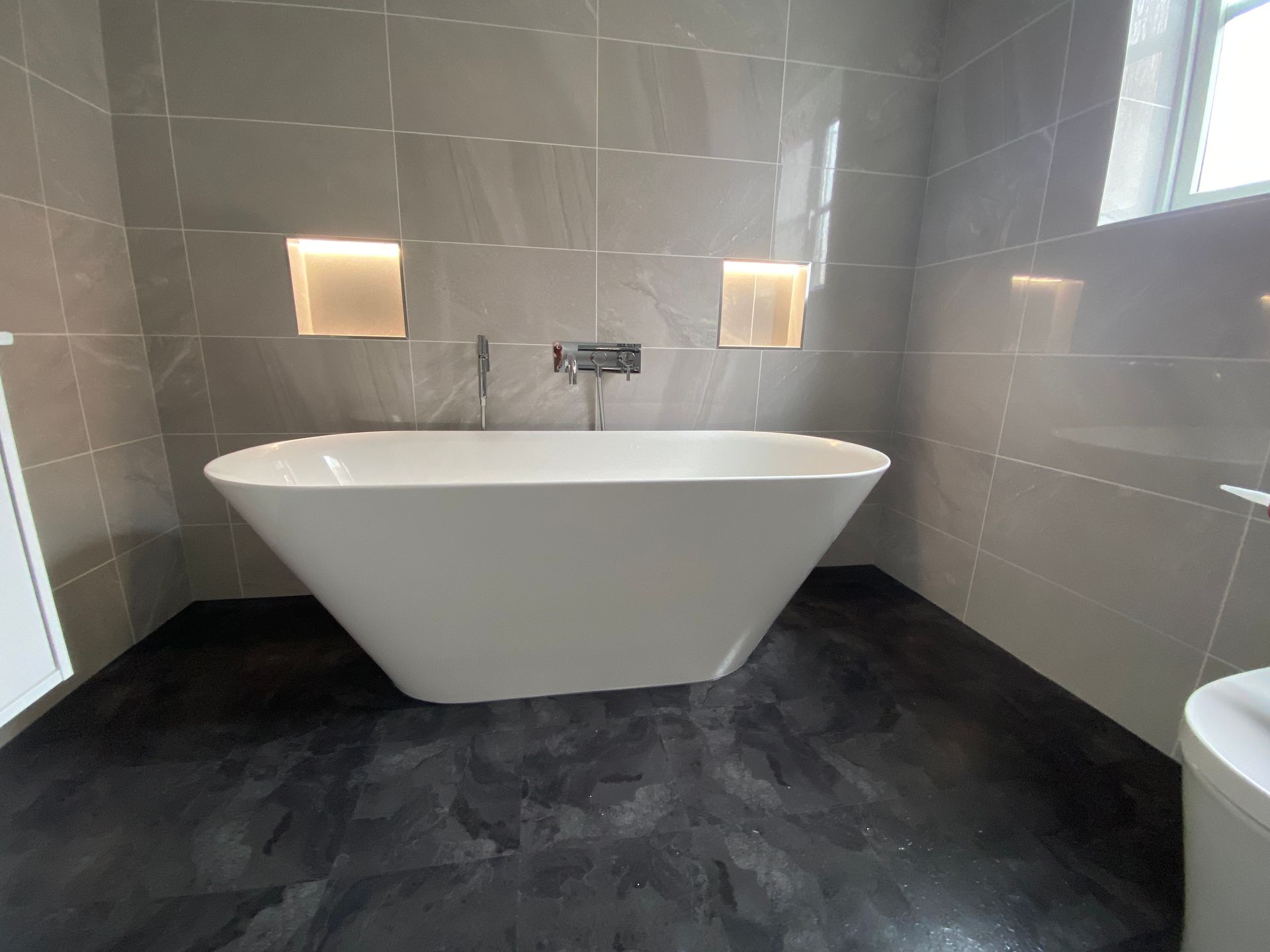 A bathroom with a bathtub and two toilets.