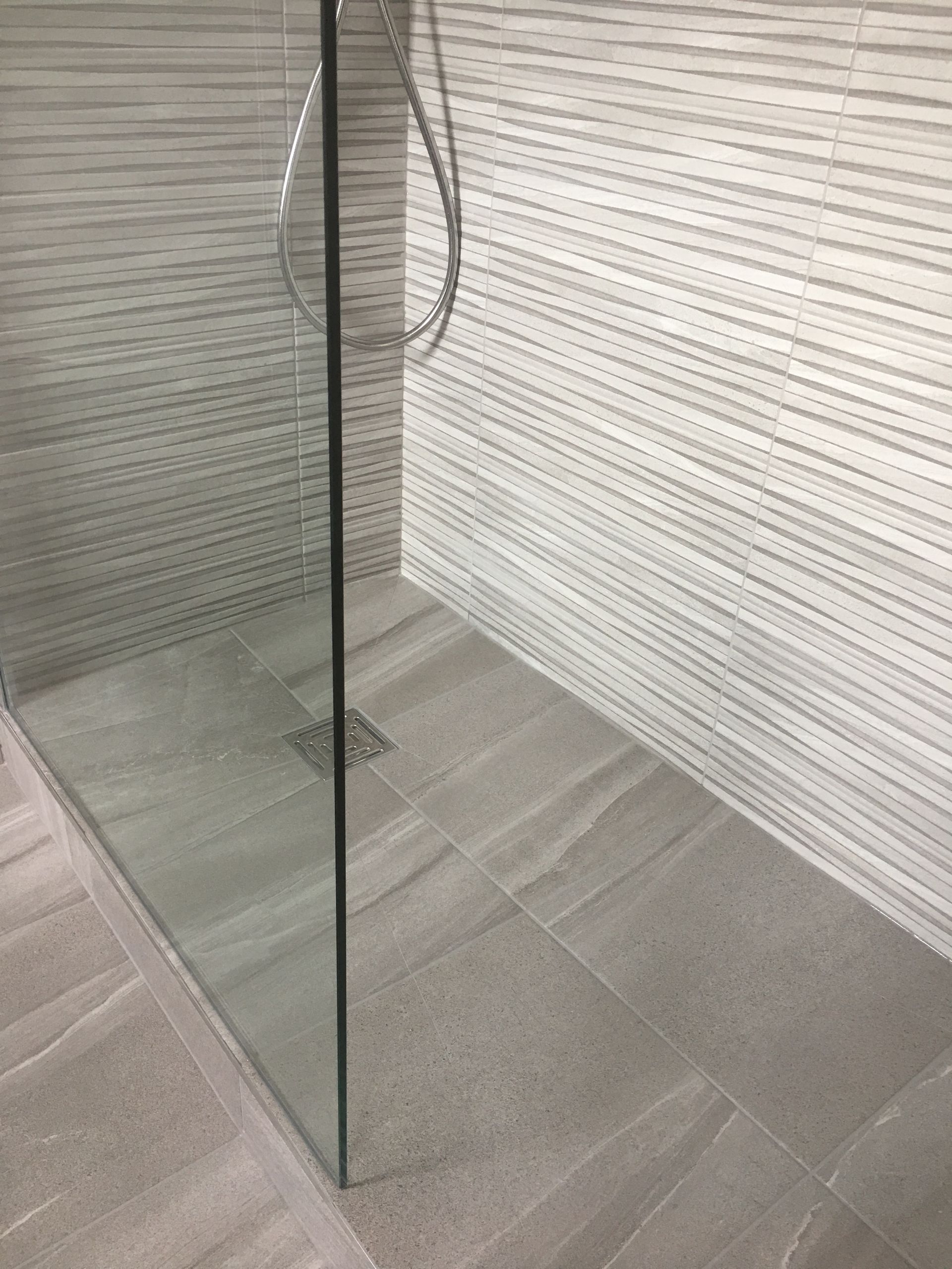 A walk in shower with a glass door and a shower head.