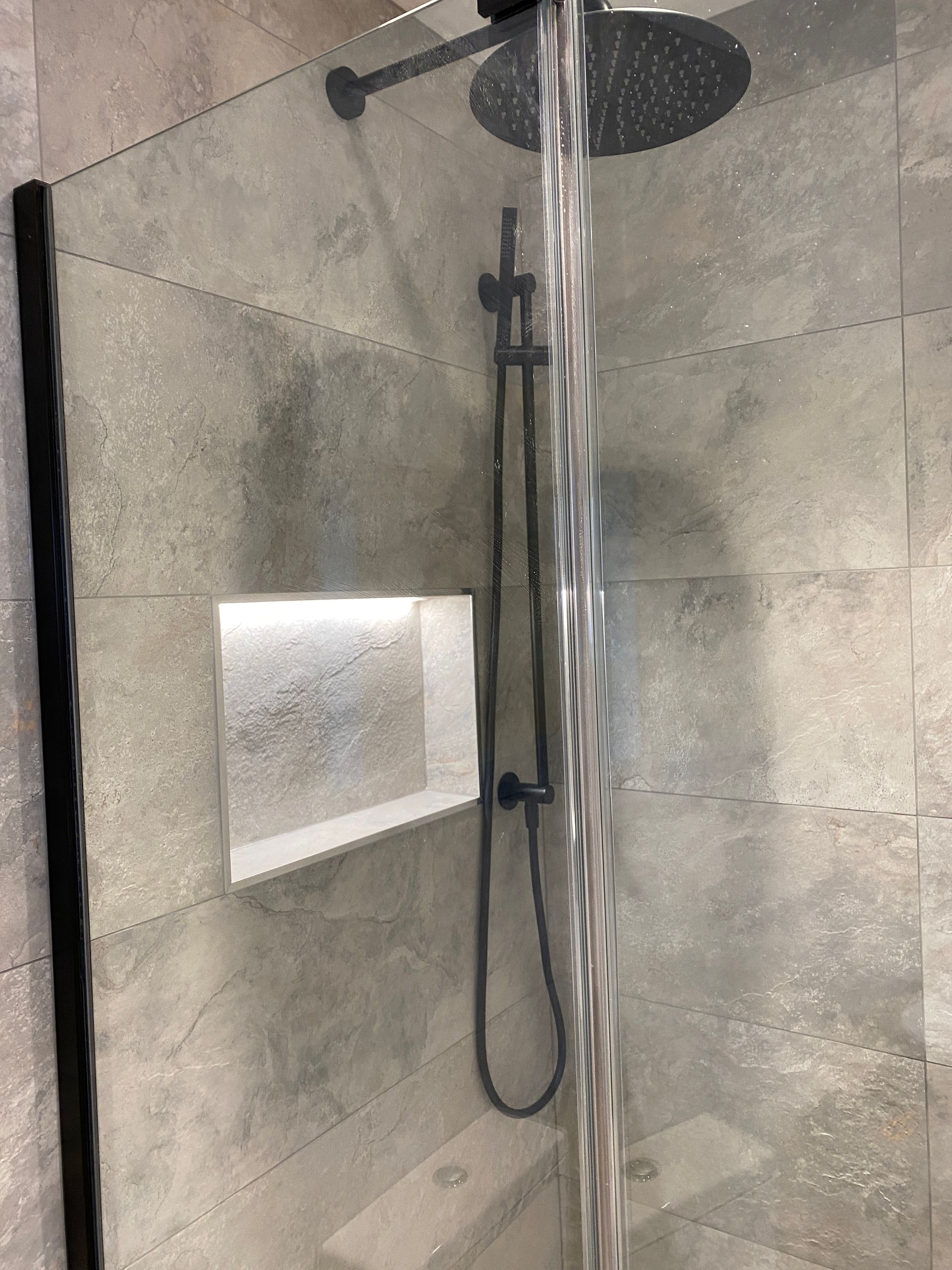 A shower with a shower head and a hose coming out of it.