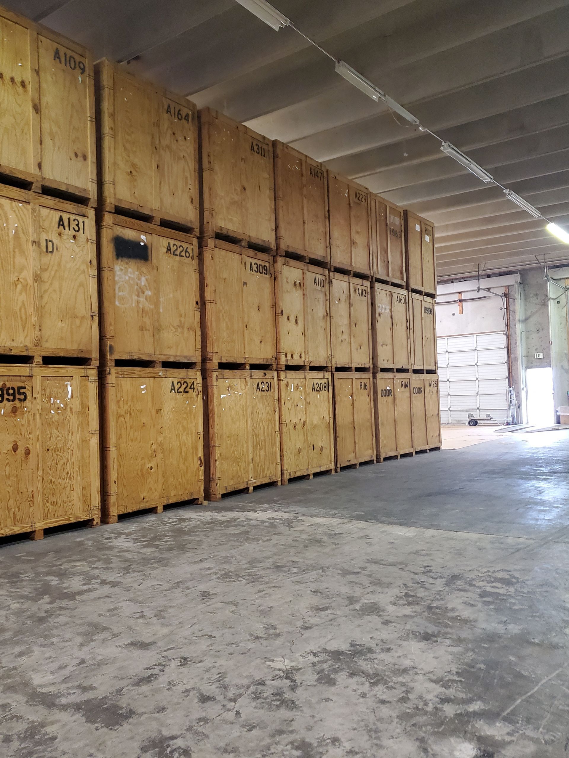 Two workers are lifting a pallet of boxes in a warehouse.