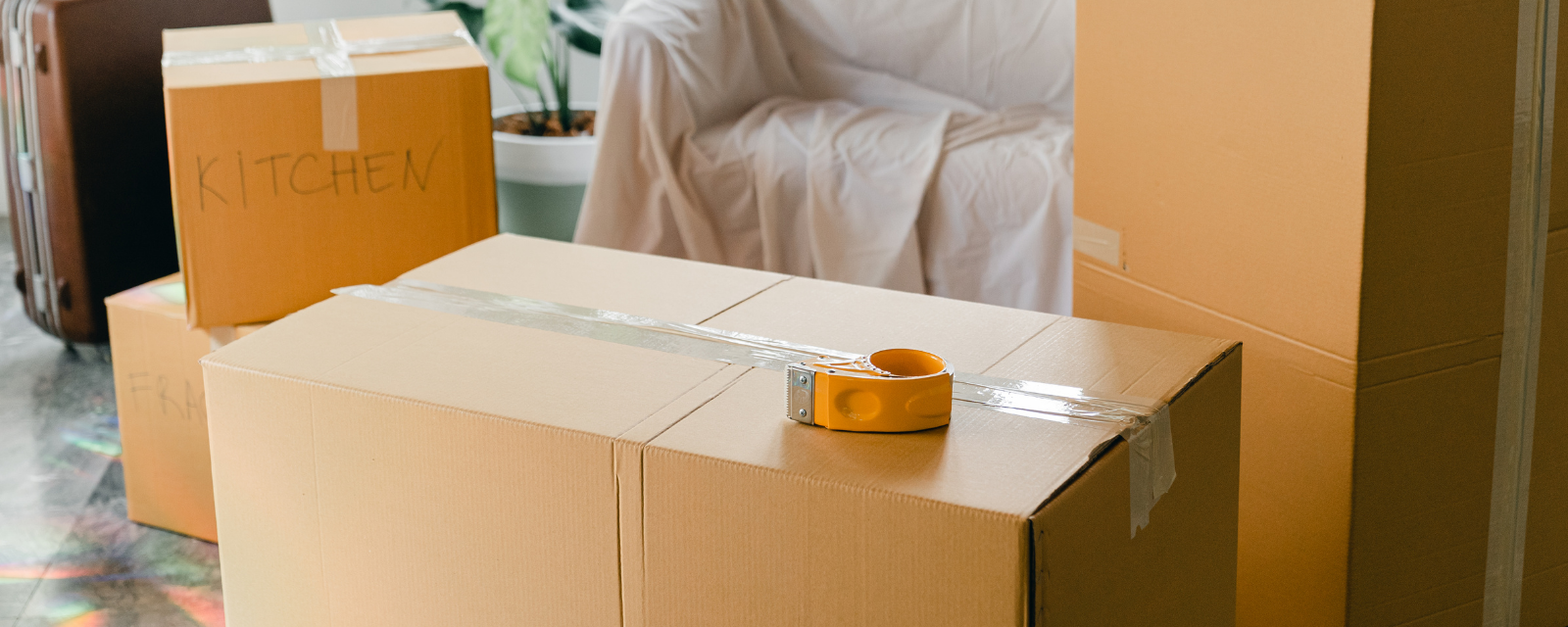 A tape measure is sitting on top of a cardboard box in a living room.