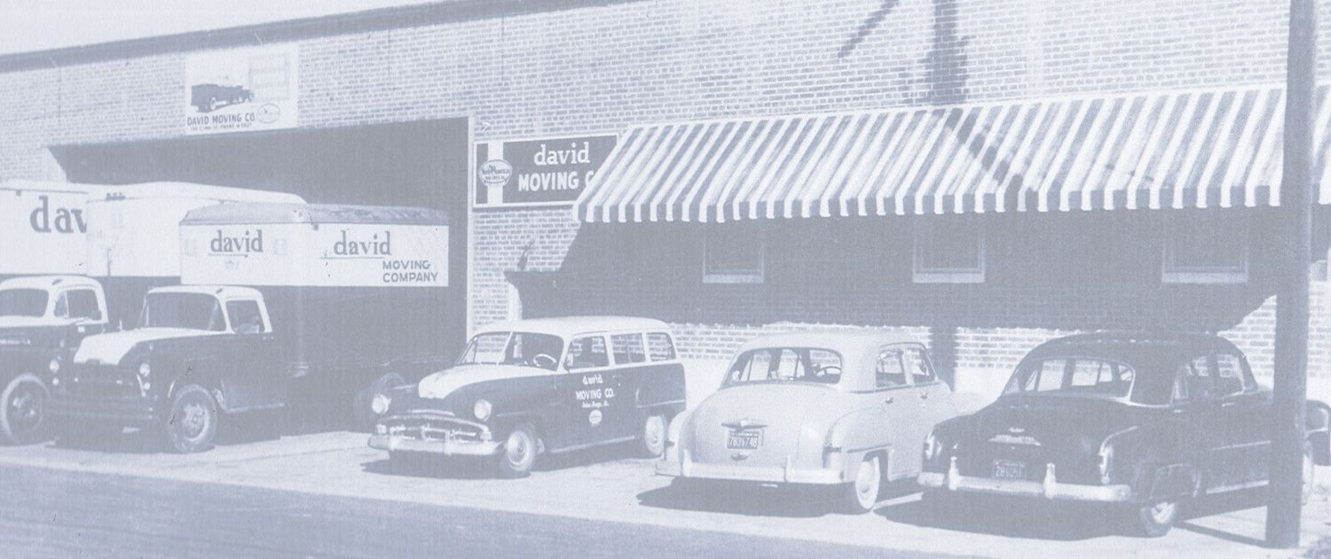 A black and white photo of cars parked in front of a building.