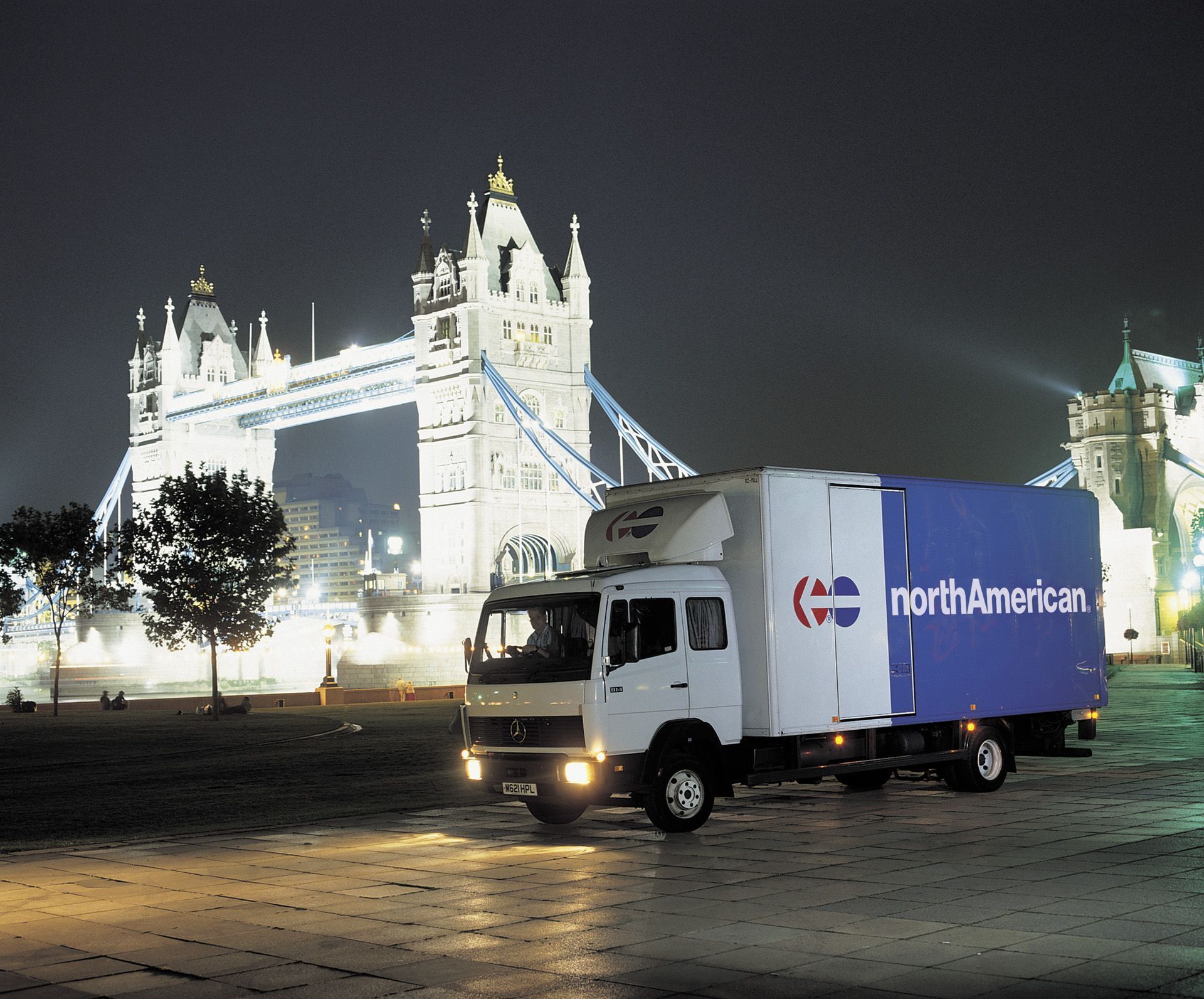 A moving truck filled with boxes and luggage is parked on the side of the road.