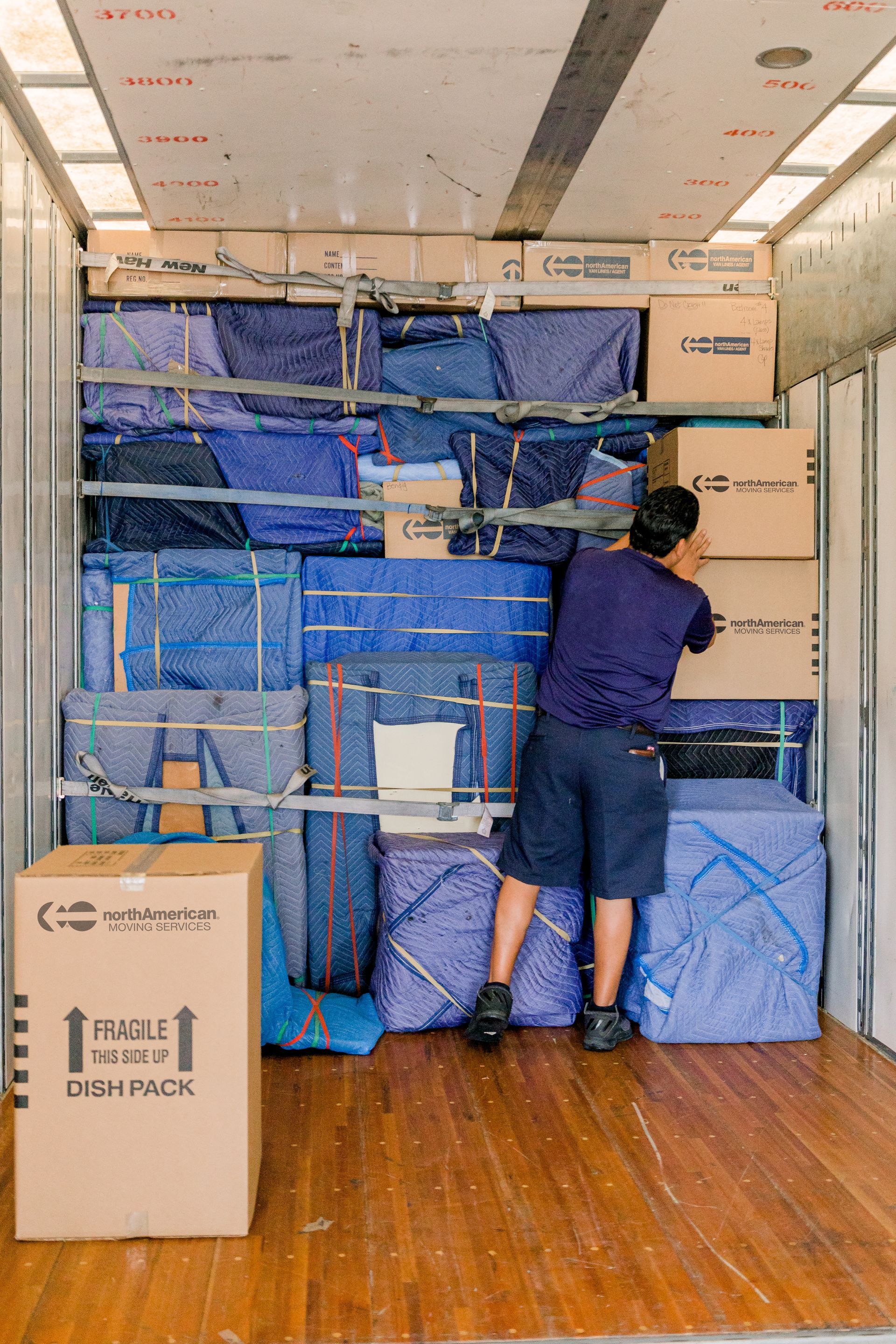 A man is standing in the back of a moving truck.