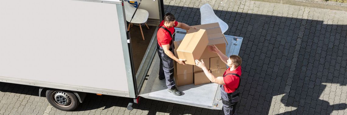 Two men are loading boxes into a moving truck.