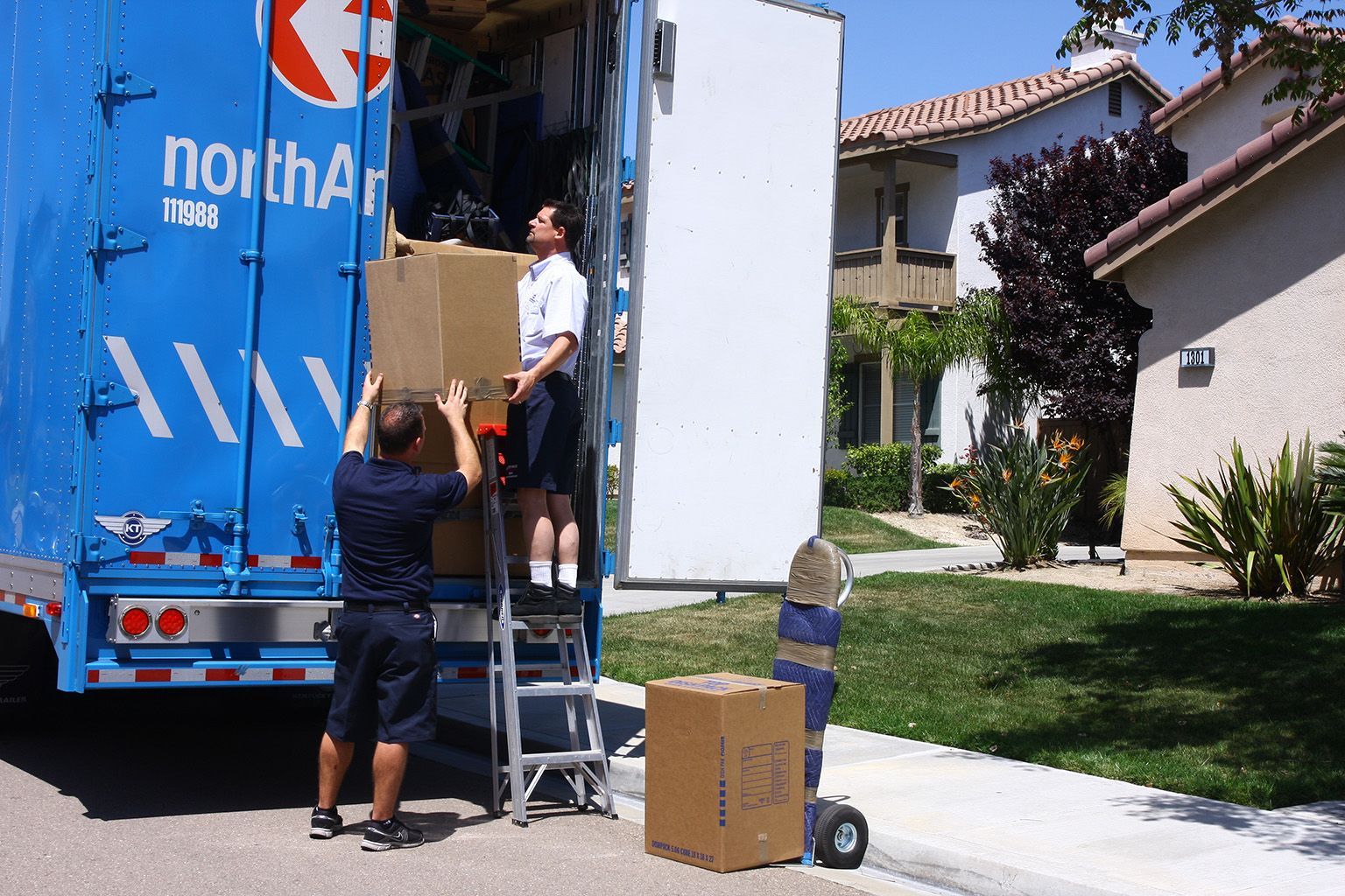 Two men are loading boxes into a north american moving truck