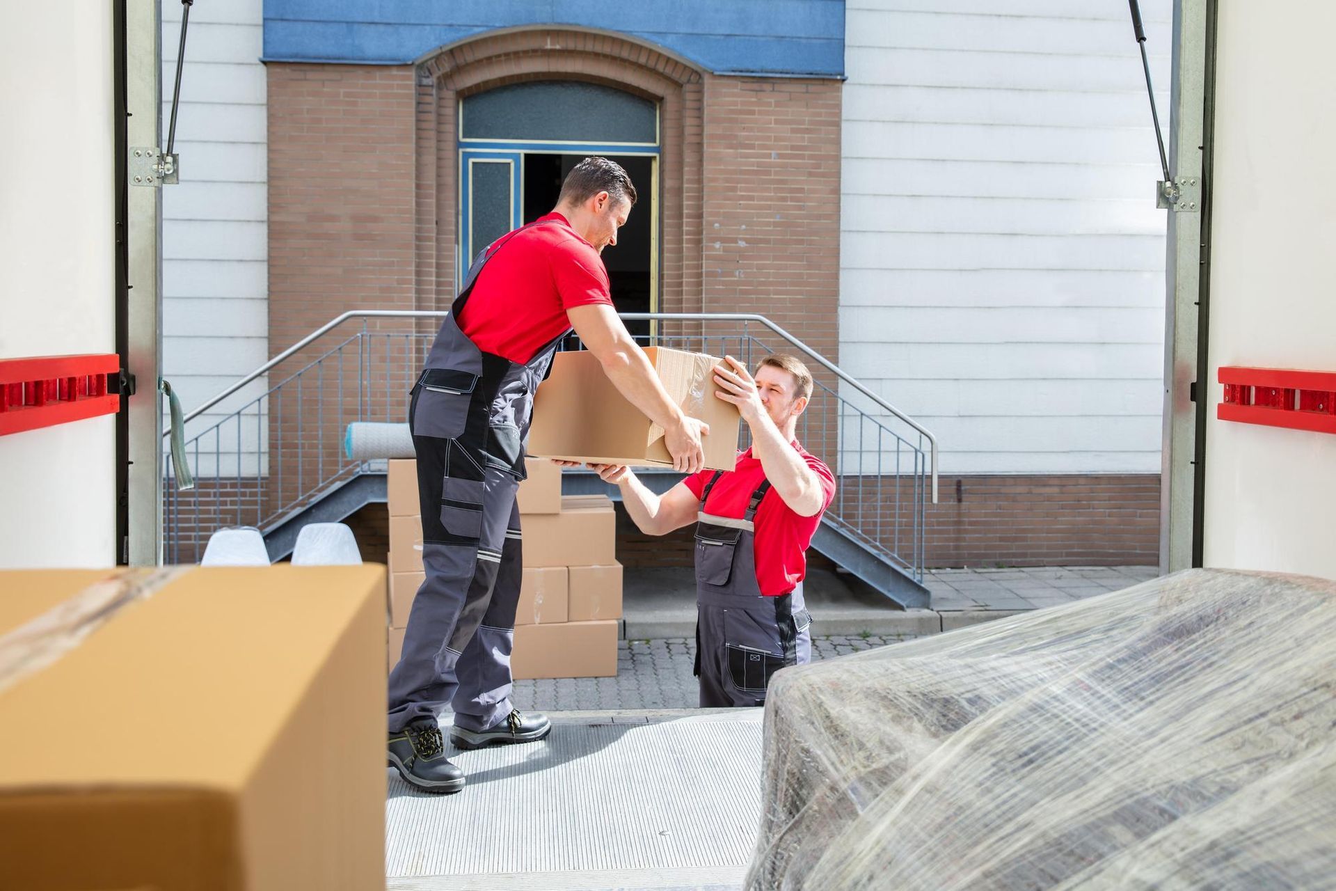 Two men are loading boxes into a moving truck.