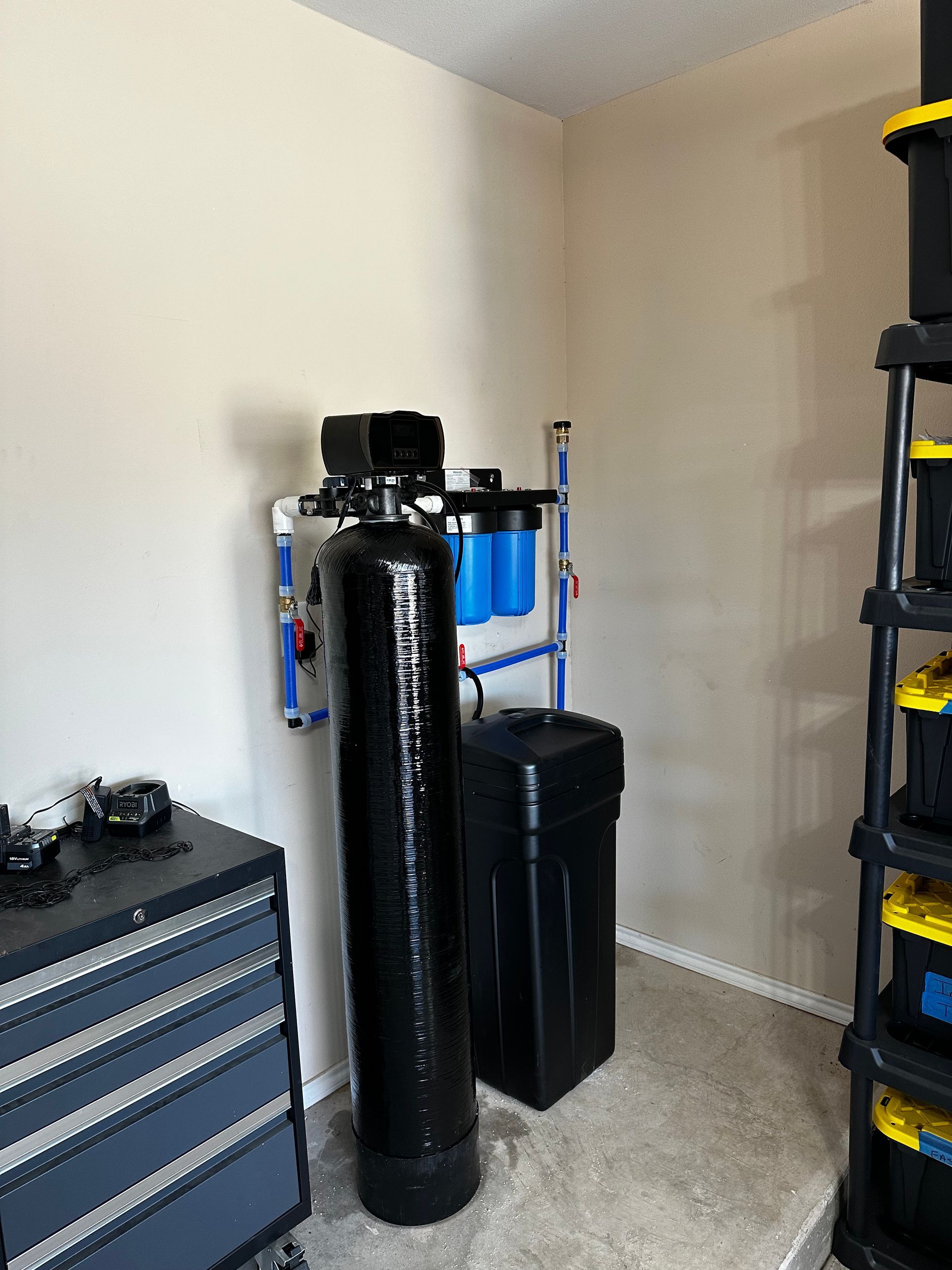A room with a water filter and a stack of storage bins.