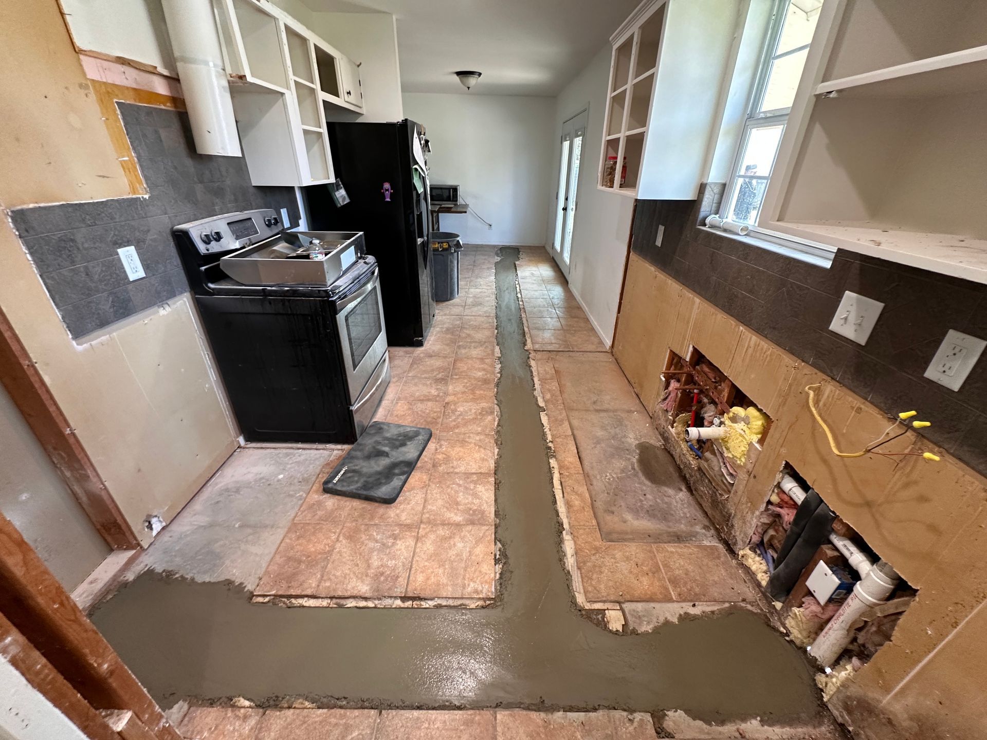 A kitchen with a stove , refrigerator , sink and cabinets being remodeled.