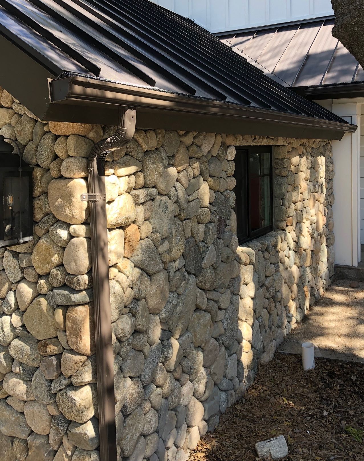 A house with a stone wall and a metal roof