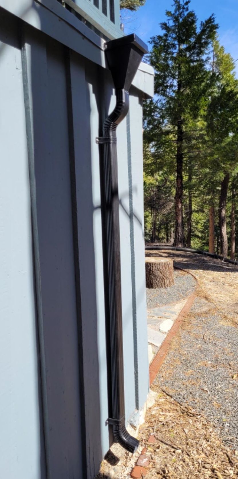 A black rain gutter is attached to the side of a building.