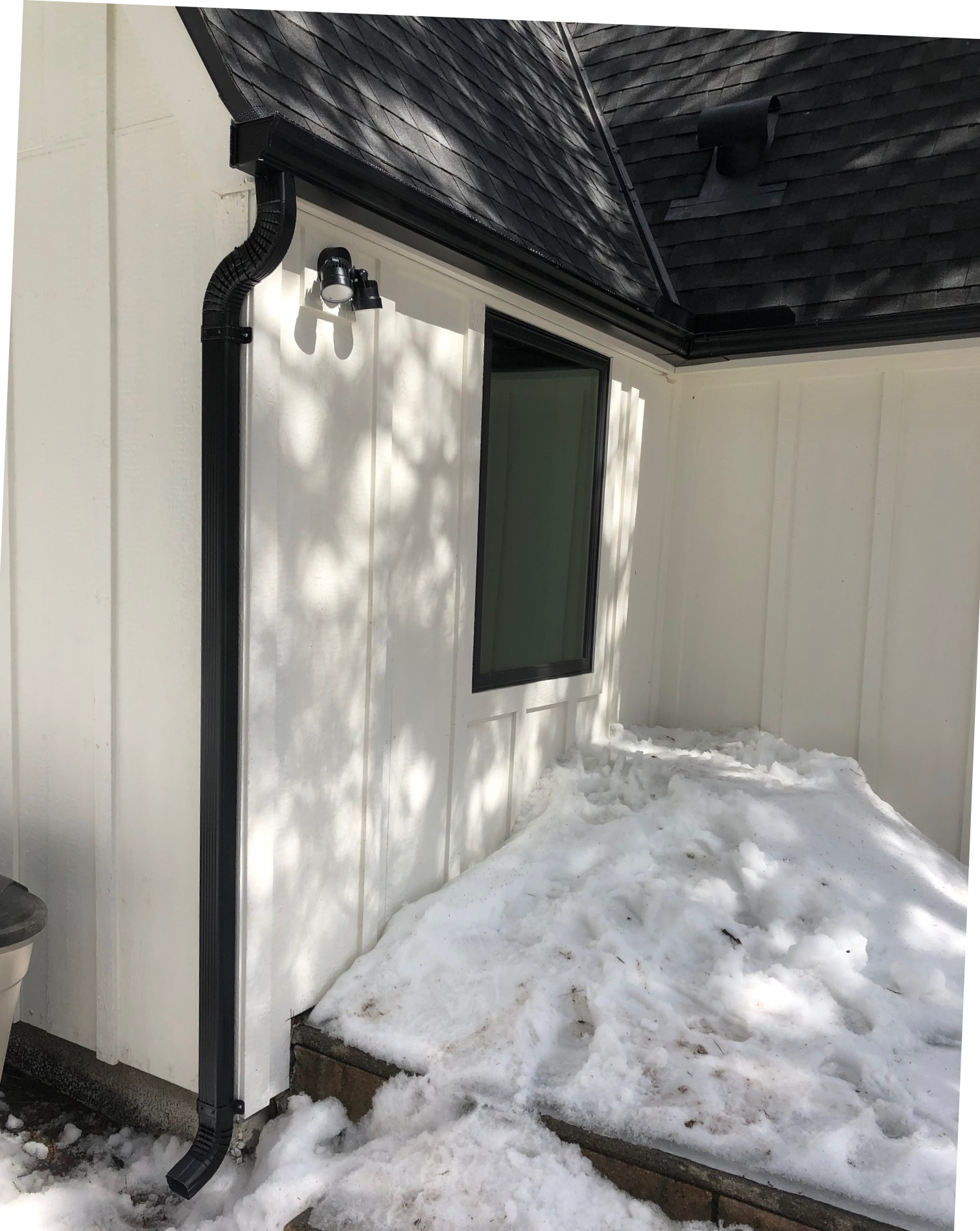 A white house with a black gutter and a window.