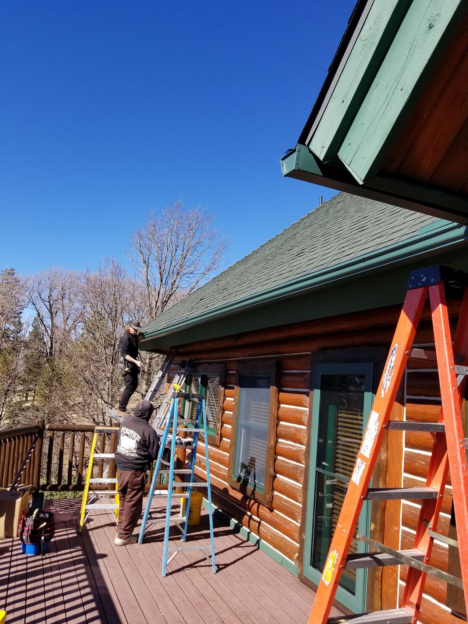 A group of people are working on the roof of a log cabin.