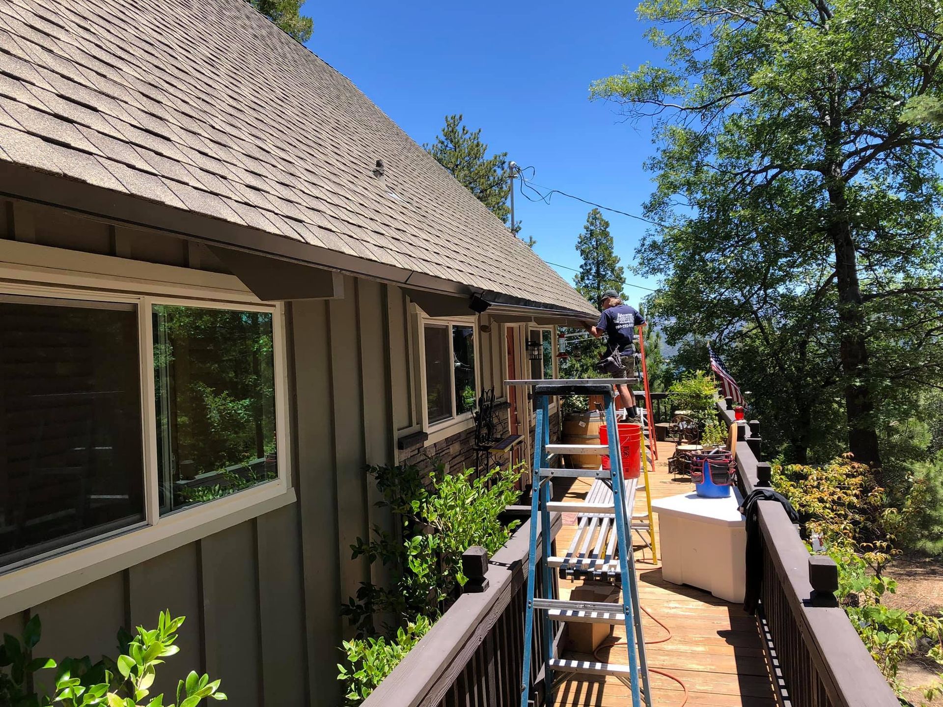 A man is standing on a ladder in front of a house.