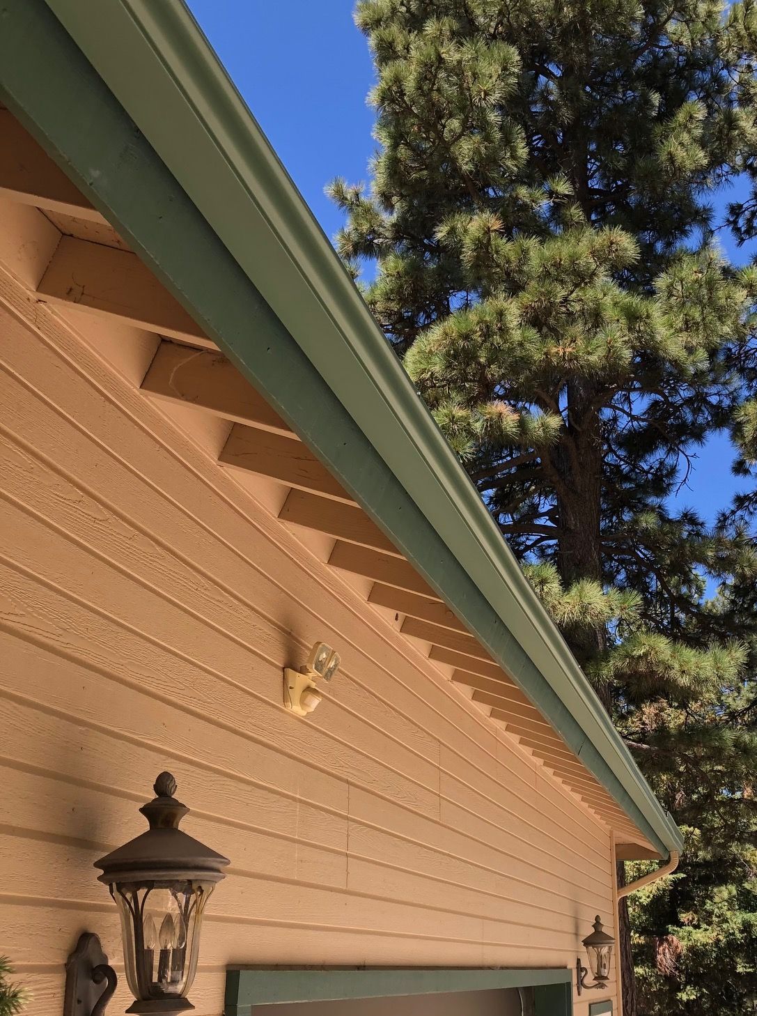 A house with a green gutter and a light on the side.