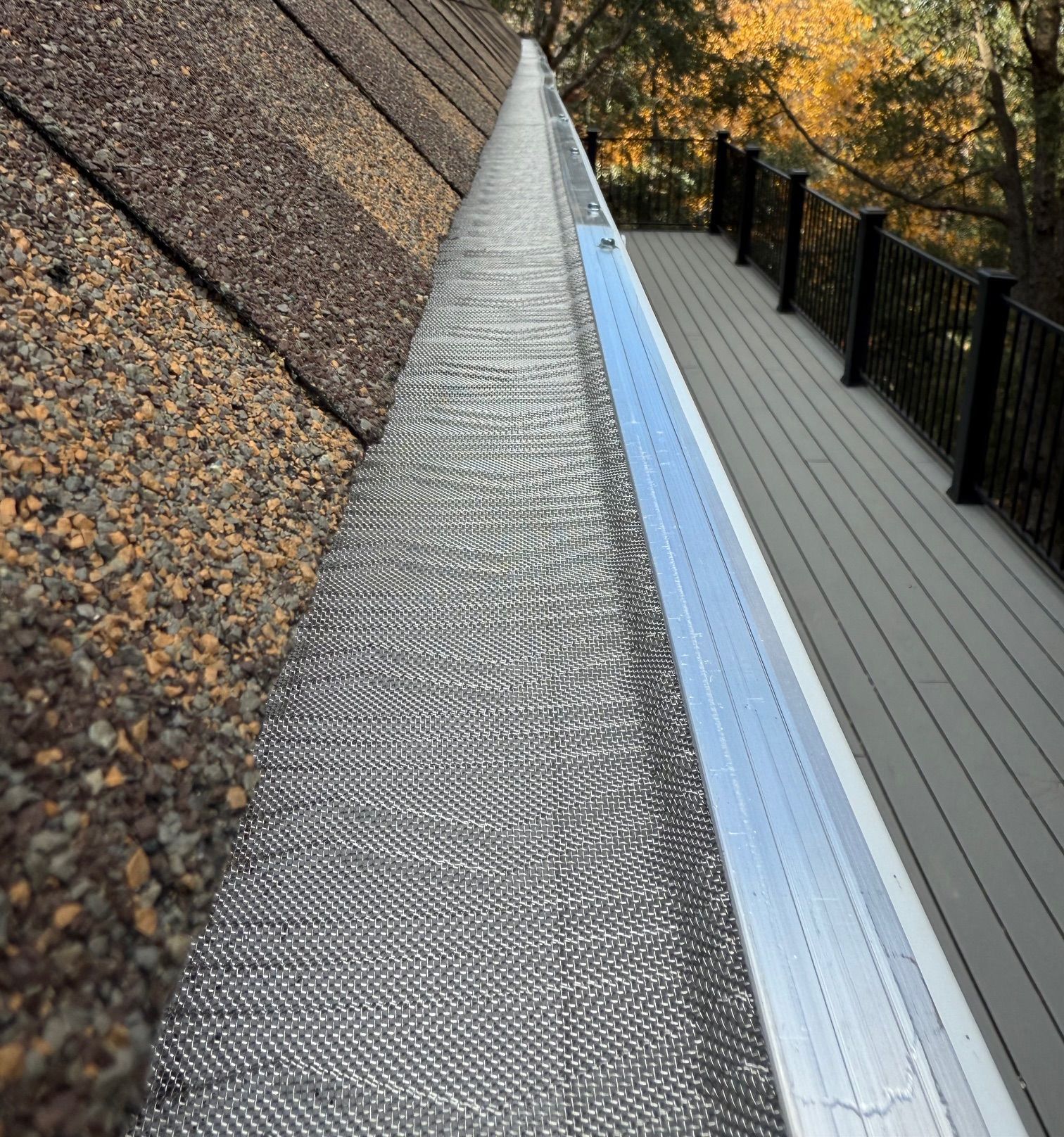 A gutter on the side of a house next to a deck.