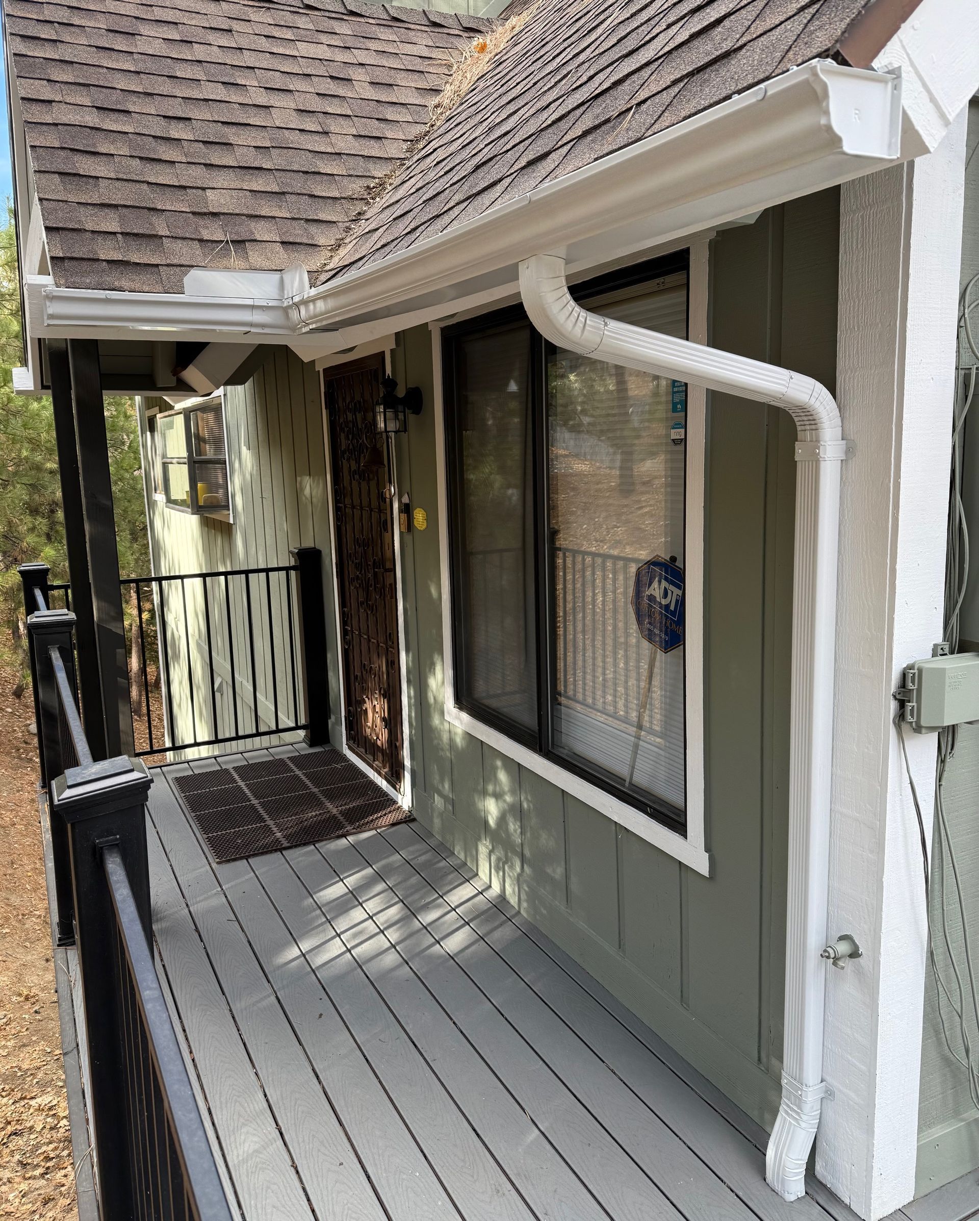 A house with a porch and a gutter on the side of it.