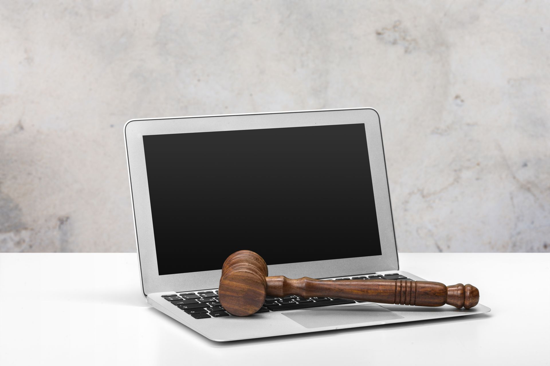 A wooden gavel is sitting on top of a laptop computer.