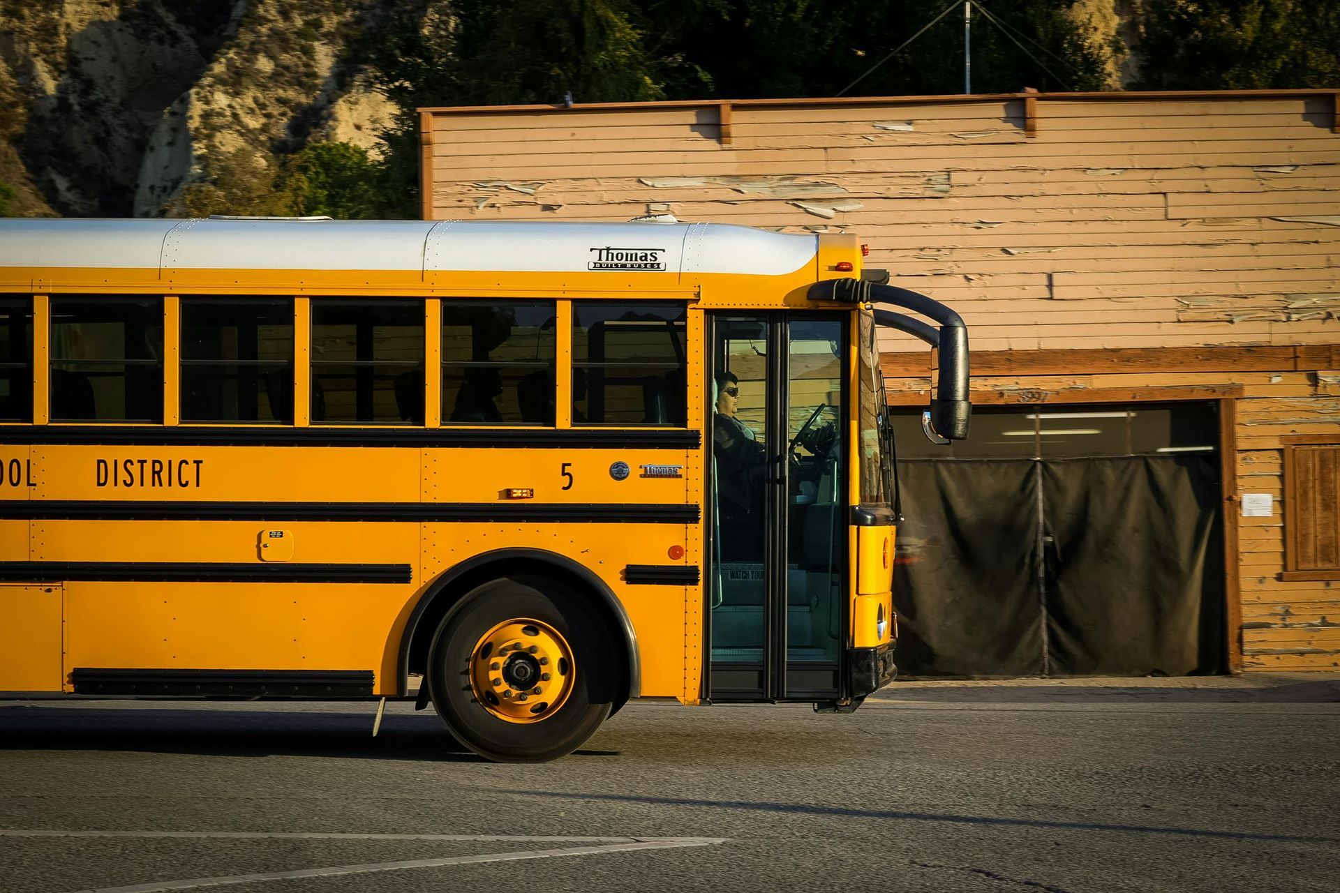 A yellow school bus is parked in front of a wooden building.