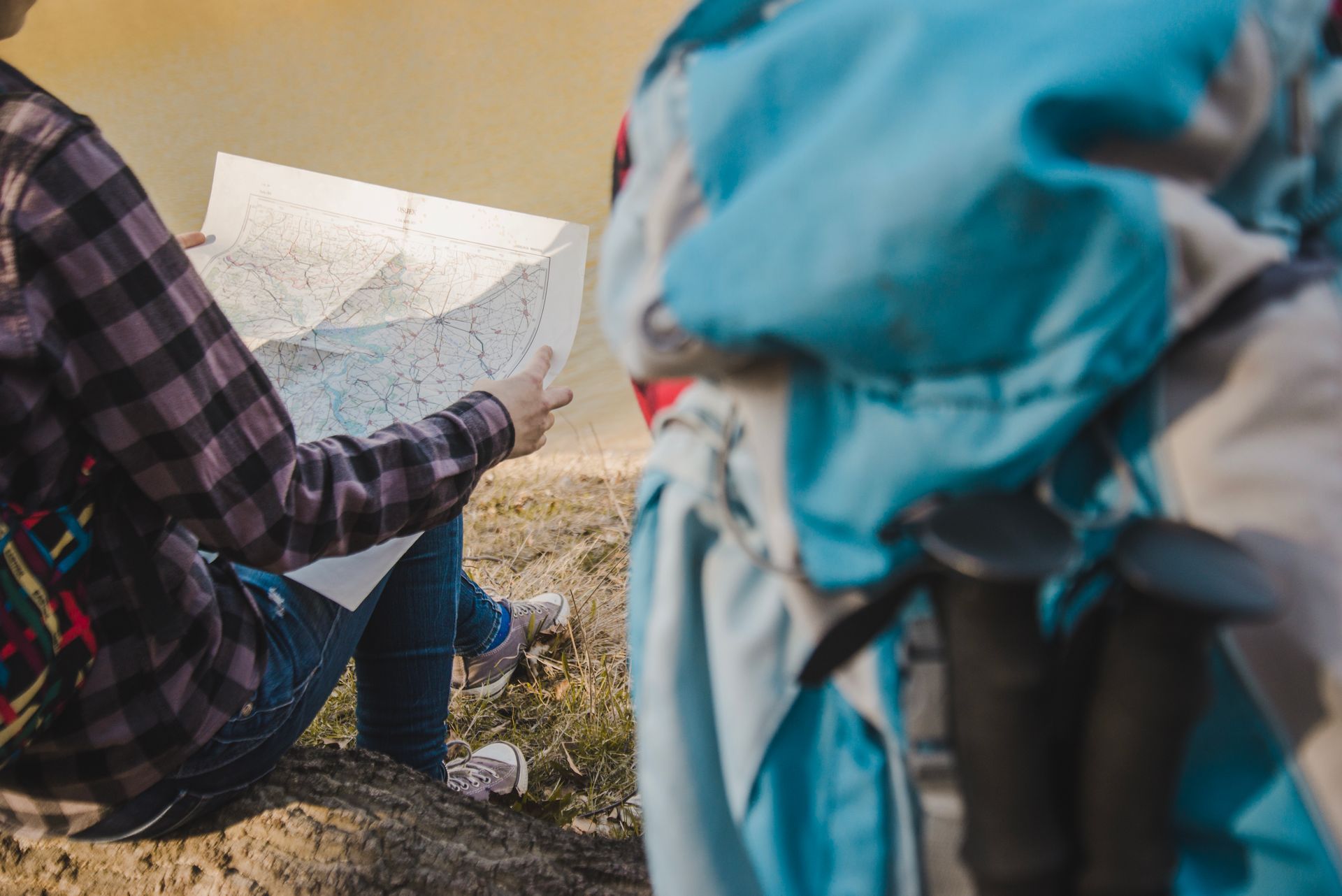 A person is sitting on the ground looking at a map.