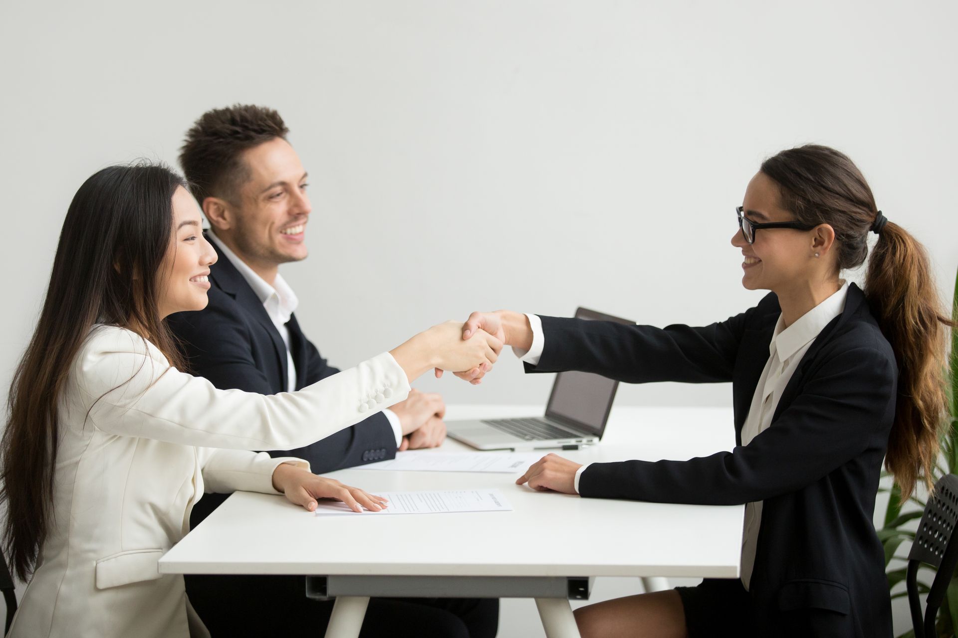 A man and a woman are shaking hands during a job interview.